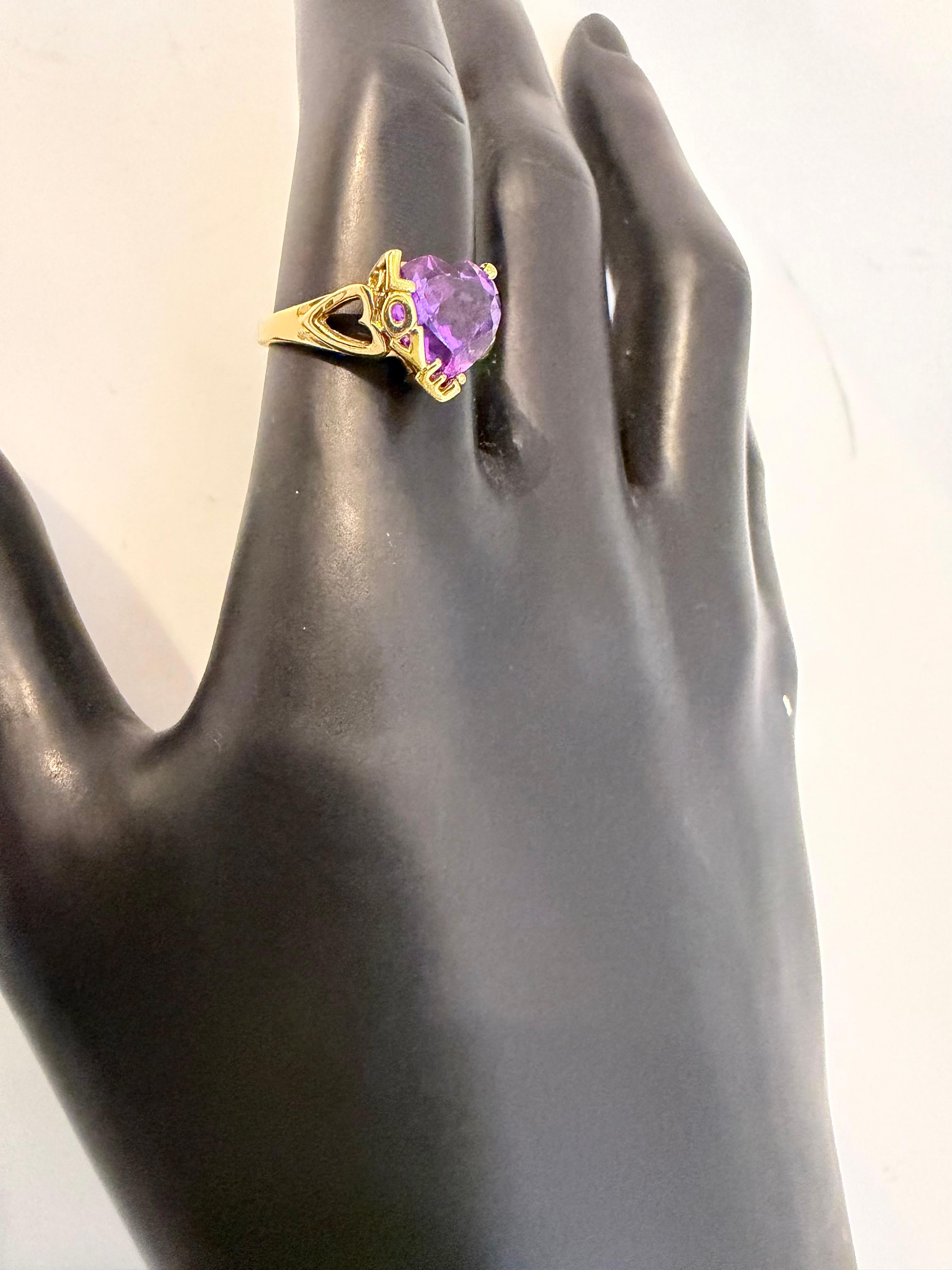 Bague cocktail en or jaune 18 carats avec améthyste en forme de coeur de 4 carats
Succession 
Cette bague contient environ 4 carats d'améthyste de haute qualité en forme de cœur et quatre lettres L O V E sont écrites sur l'un des côtés du