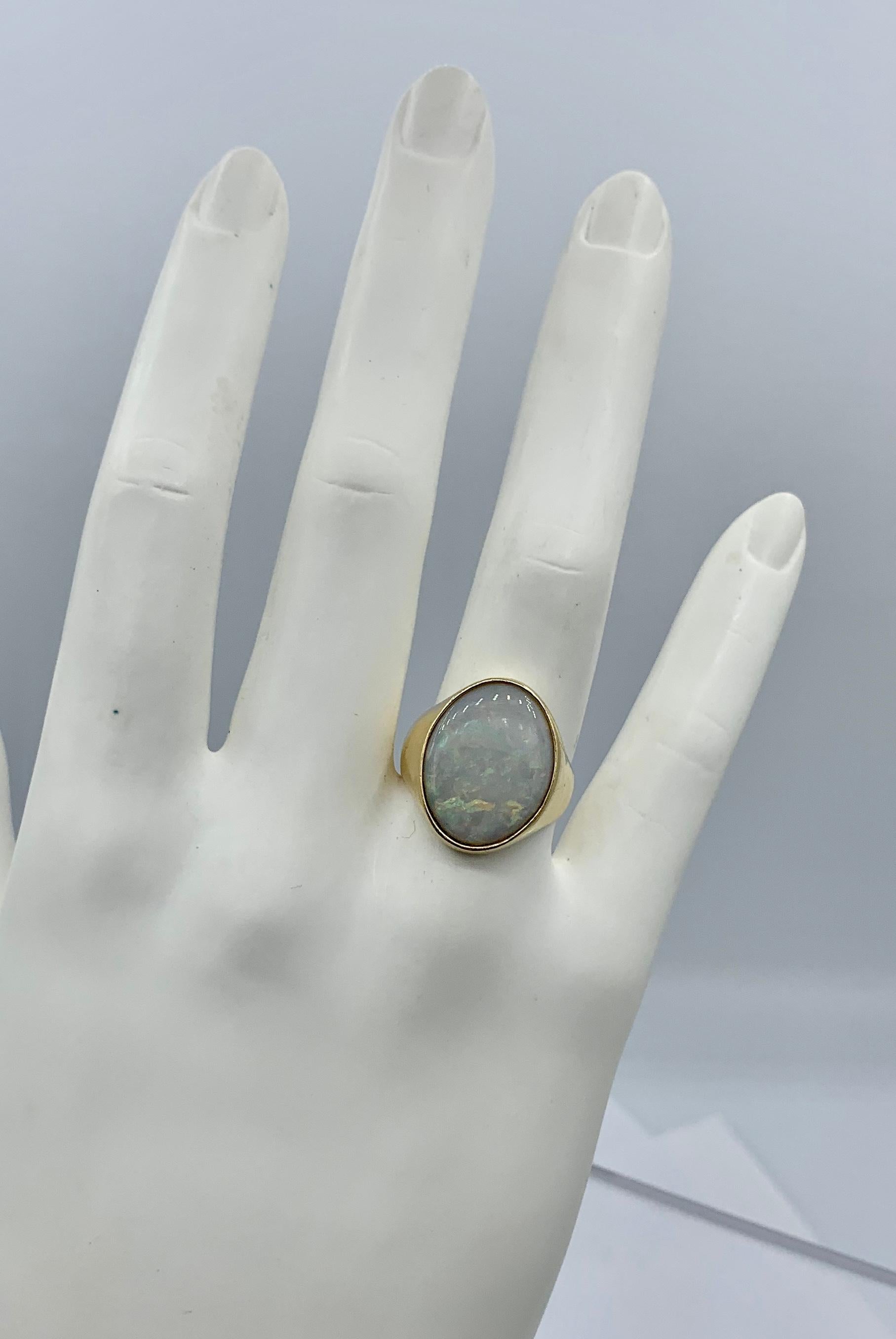 THIS IS A WONDERFUL RETRO MID-CENTURY MODERN FOUR CARAT OPAL RING IN 14K YELLOW GOLD WITH A STUNNING OVAL OPAL CABOCHON GEM.
The effect of the gorgeous natural opal in the classic mid-century modern design in 14 Karat yellow gold create a magical