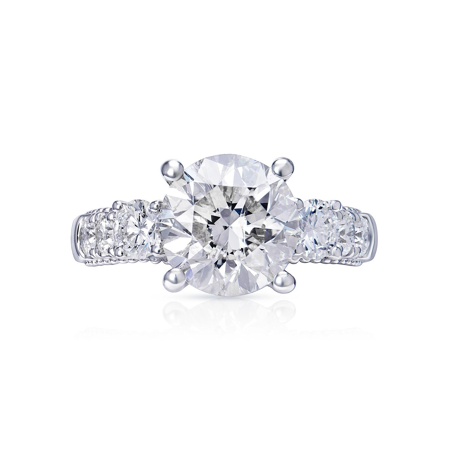 Center Earth Mined Diamond:
Carat Weight: 3.03 Carats
Color: G
Clarity: VS2
Style: Round Brilliant Cut

Ring:
Total Carats:3.96 Carats
Metal: 18 karat White Gold 5.80 Grams
Diamonds: 0.93 Carats
Style: Round Brilliant Cut
Setting: Three-stone & 4