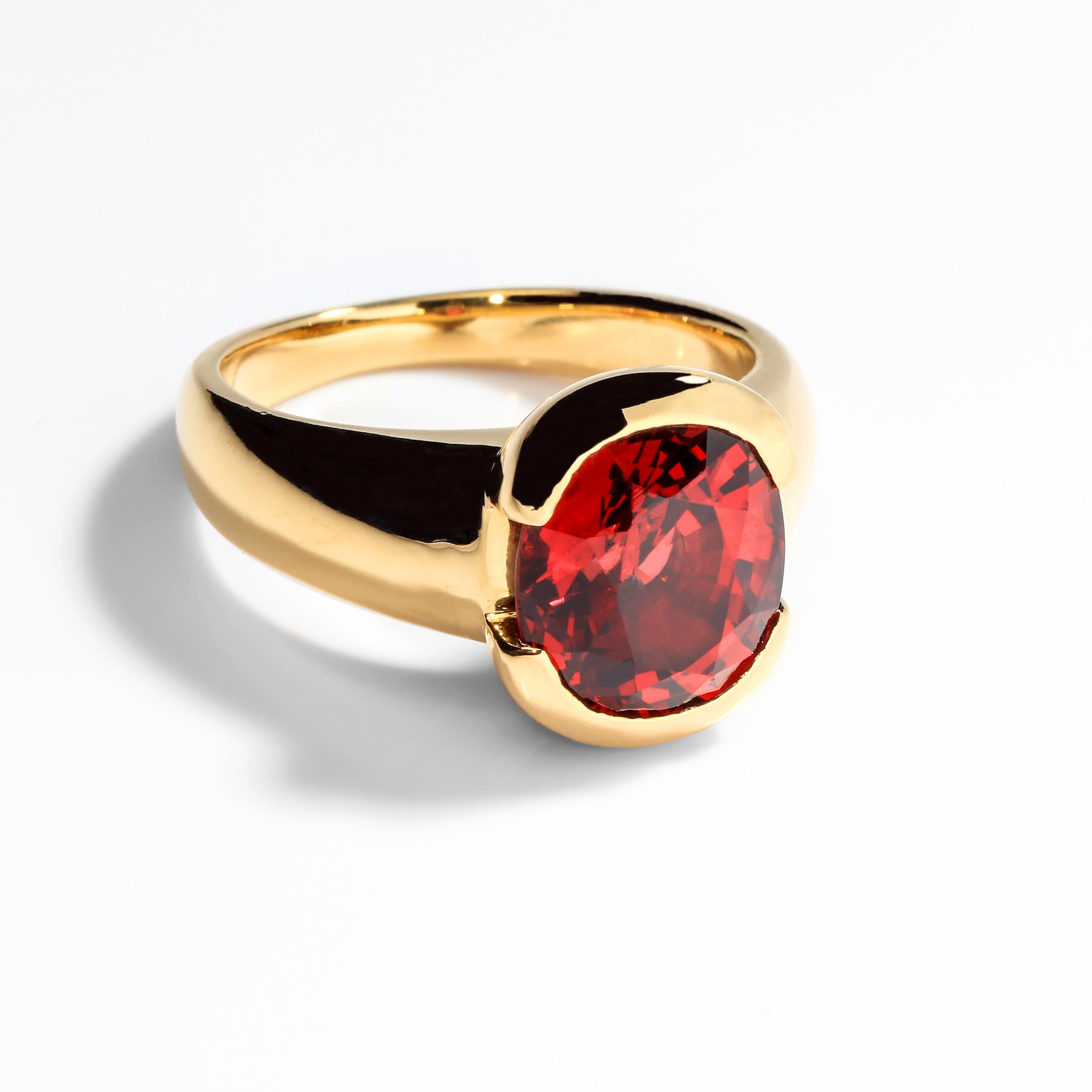 This 10mm x 9mm 4-carat oval-cut spinel is the pleasing color we always seek in a ruby but rarely seem to find —most are either too pink, too purple, too dark or too small.  This large and bright stoplight of a gem is situated within a half-bezel