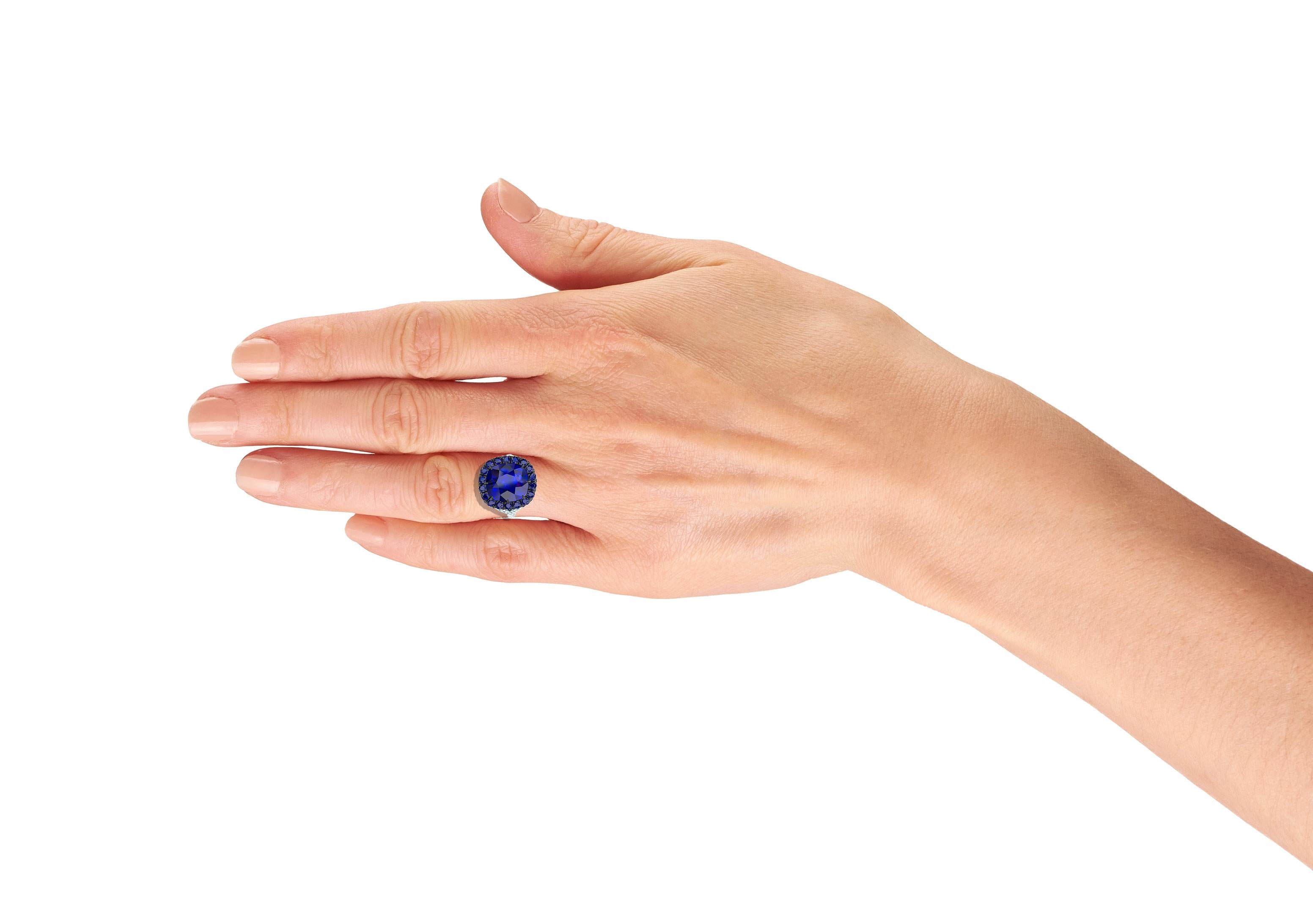 A beautiful blue sapphire and diamond ring has a center stone that's cushion cut and has deep rich blue color. The center stone is surrounded by over 1.3 carats of matching blue sapphires set in blackened silver and gold. The sapphires are accented