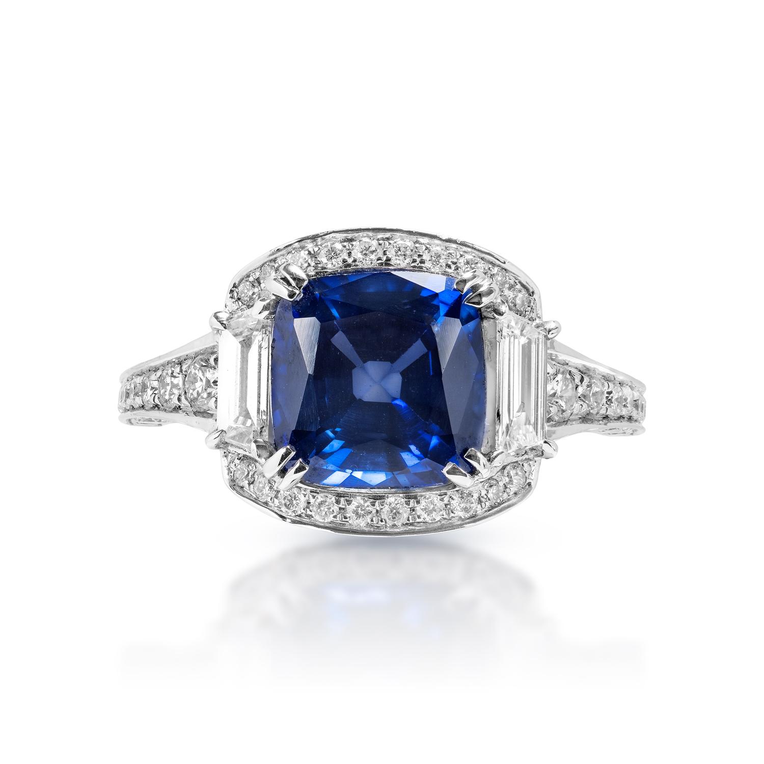 Center Blue Sapphire:
Carat Weight: 3.15 Carats
Color: Blue Sapphire - Diffused J’adore Sapphire 
Style: Vintage Inspired Step Cut


Trapezoid Diamond 
Carat Weight: 1.30 Carats
Shape: Trapezoid Diamond 
Setting: Accent diamonds
Metal: 18 Karat