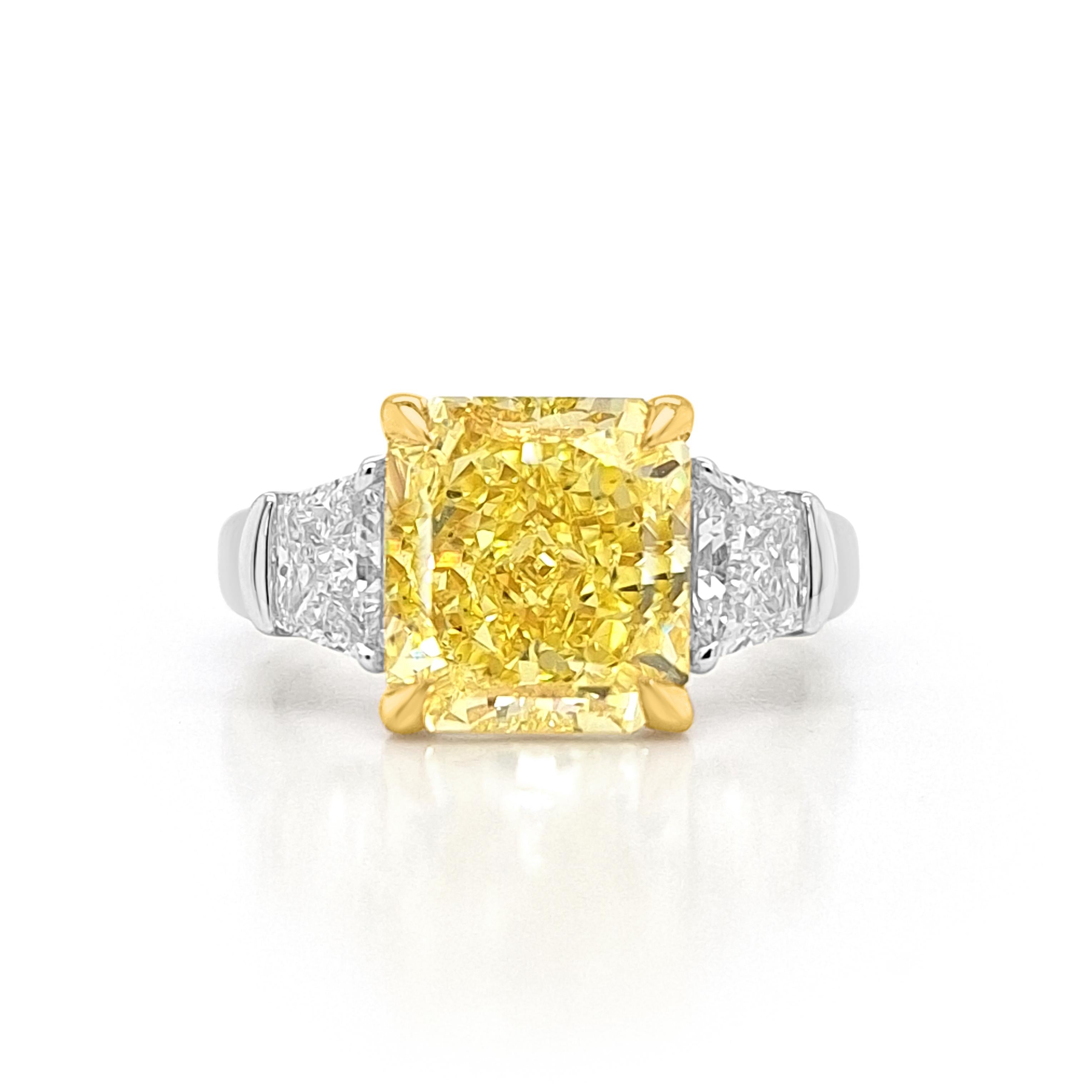 Questo diamante giallo intenso Nature Fancy certificato GIA è al centro della scena con la sua rara e vibrante tonalità dorata, che irradia calore e opulenza. Circondato da diamanti bianchi trapezoidali, il design ne esalta il fuoco e la