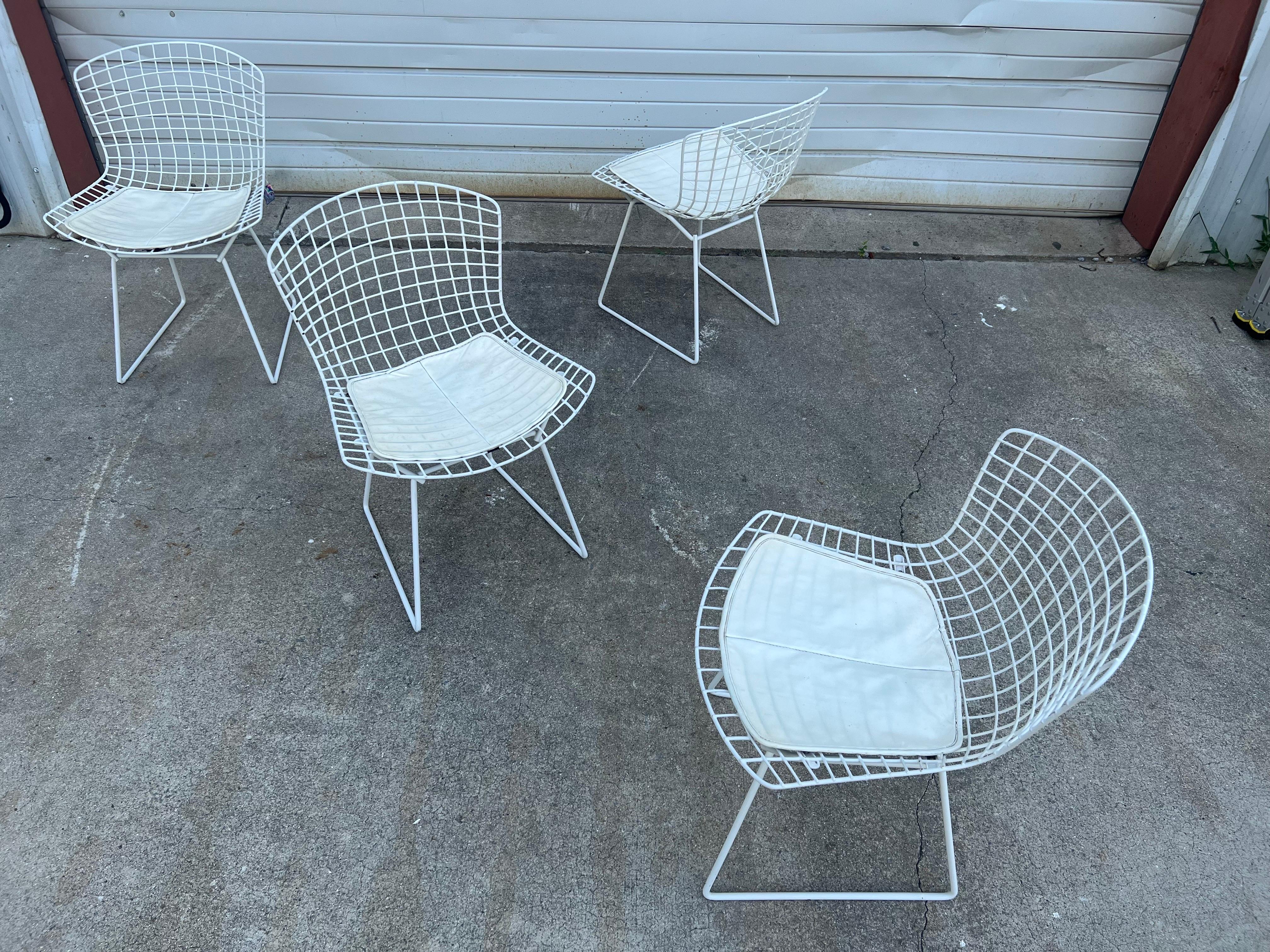 Four chairs designed by Harry Bertoia for Knoll Manufacturing, circa 1960s. These chairs have several ways in which they can function: dining, outdoor, and accent. Each chair has its original white finish, with minor chipping and wear throughout.