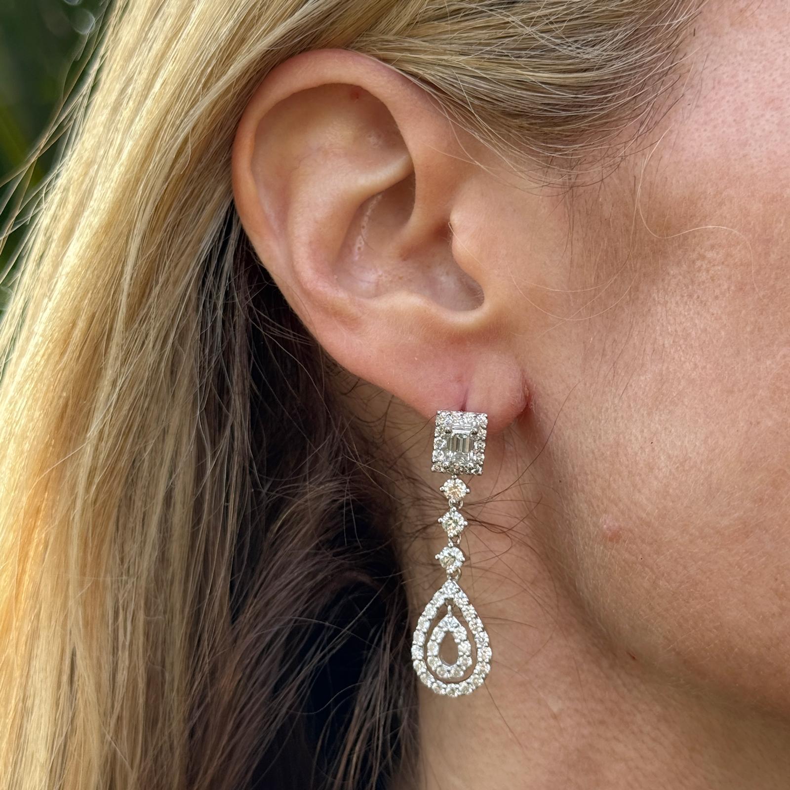 Questi eleganti orecchini a pendente con diamanti presentano un design sofisticato e senza tempo. Ogni orecchino presenta un brillante diamante taglio smeraldo nella parte superiore, per un totale di 1,00 carati (colore G-H, purezza VS2-SI1), che