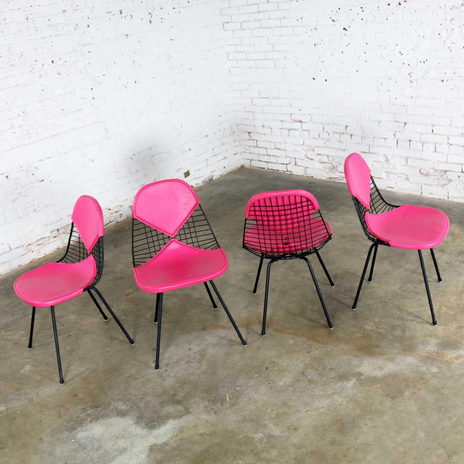 Fabulous set of four DKX-2 wire bikini shell chairs on X bases with Hot Pink Naugahyde bikini covers designed by Charles and Ray Eames for Herman Miller. They are in wonderful vintage restored condition overall. The chairs have had some factory weld