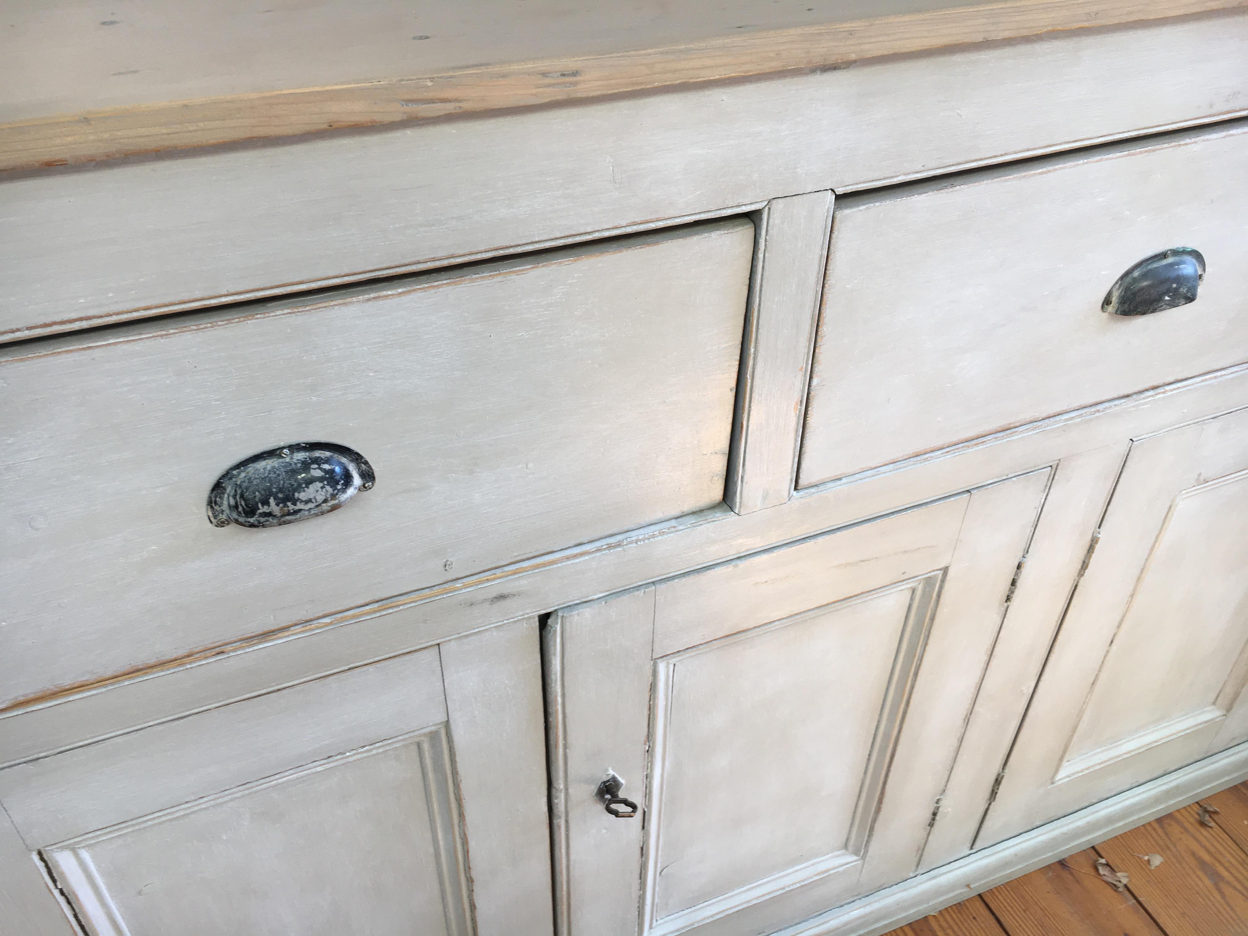 A gorgeous light grey painted base with a light scrubbed pine top and metal pulls, combined with 2 locks and keys. If that weren't enough there is much storage space available inside with shelves. A really, really good looking piece