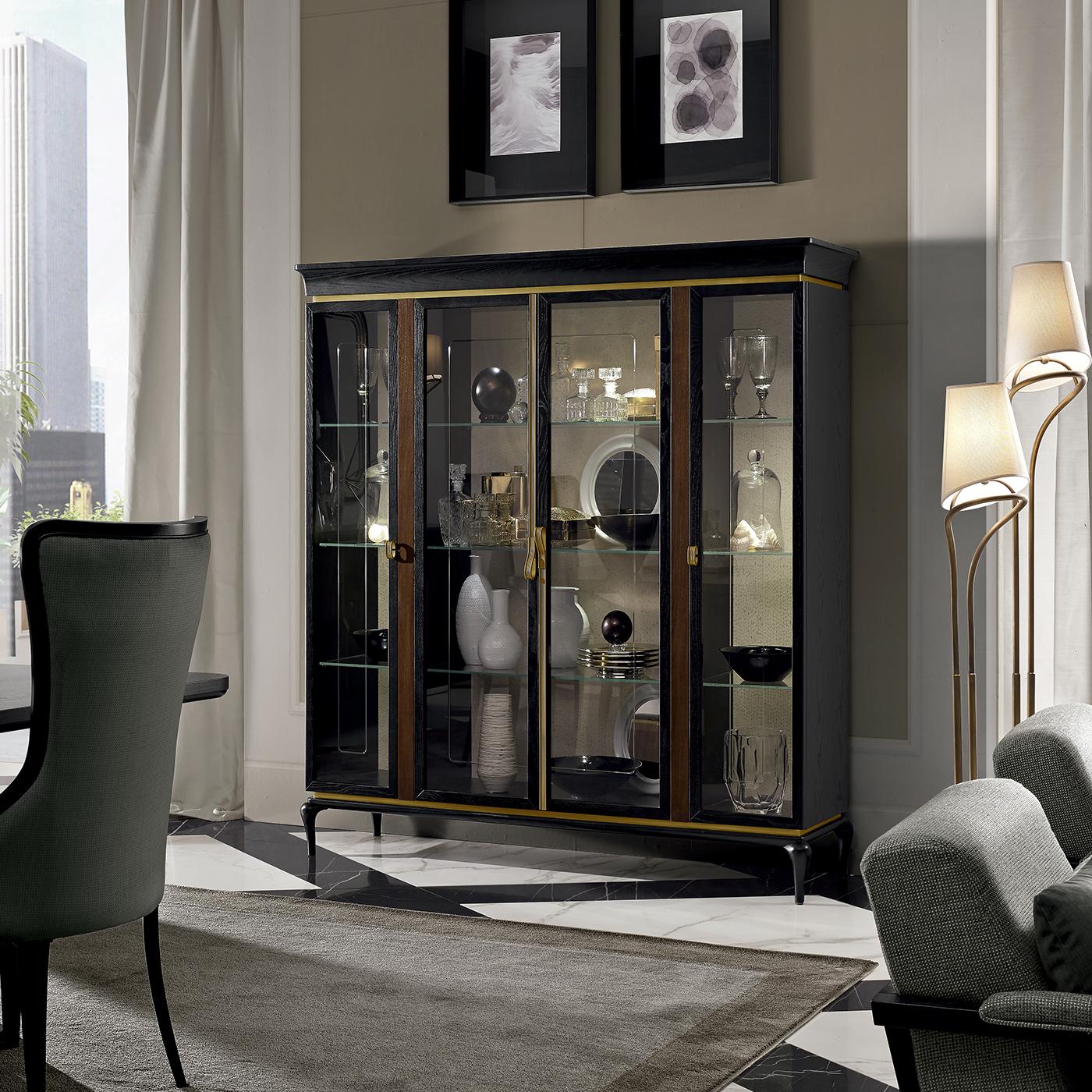 Plush sophistication and functionality merge harmoniously in this splendid four-door display cabinet. Durable and sturdy, this piece is made of Canaletto walnut-veneered MDF and plywood with a burnished brass profile, while its base is in solid ash