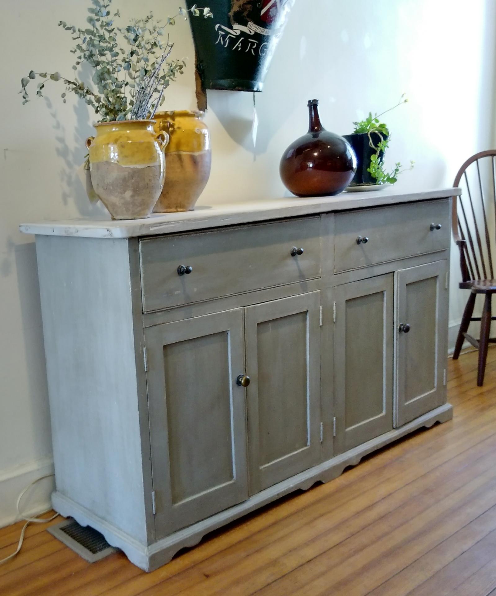 It's the old brass knobs and light pickled top that get your attention on this functional dresser base. Just the right size: not too large, with plenty of storage. The paint color is a very soft grey-green that is both country and elegant. This is a