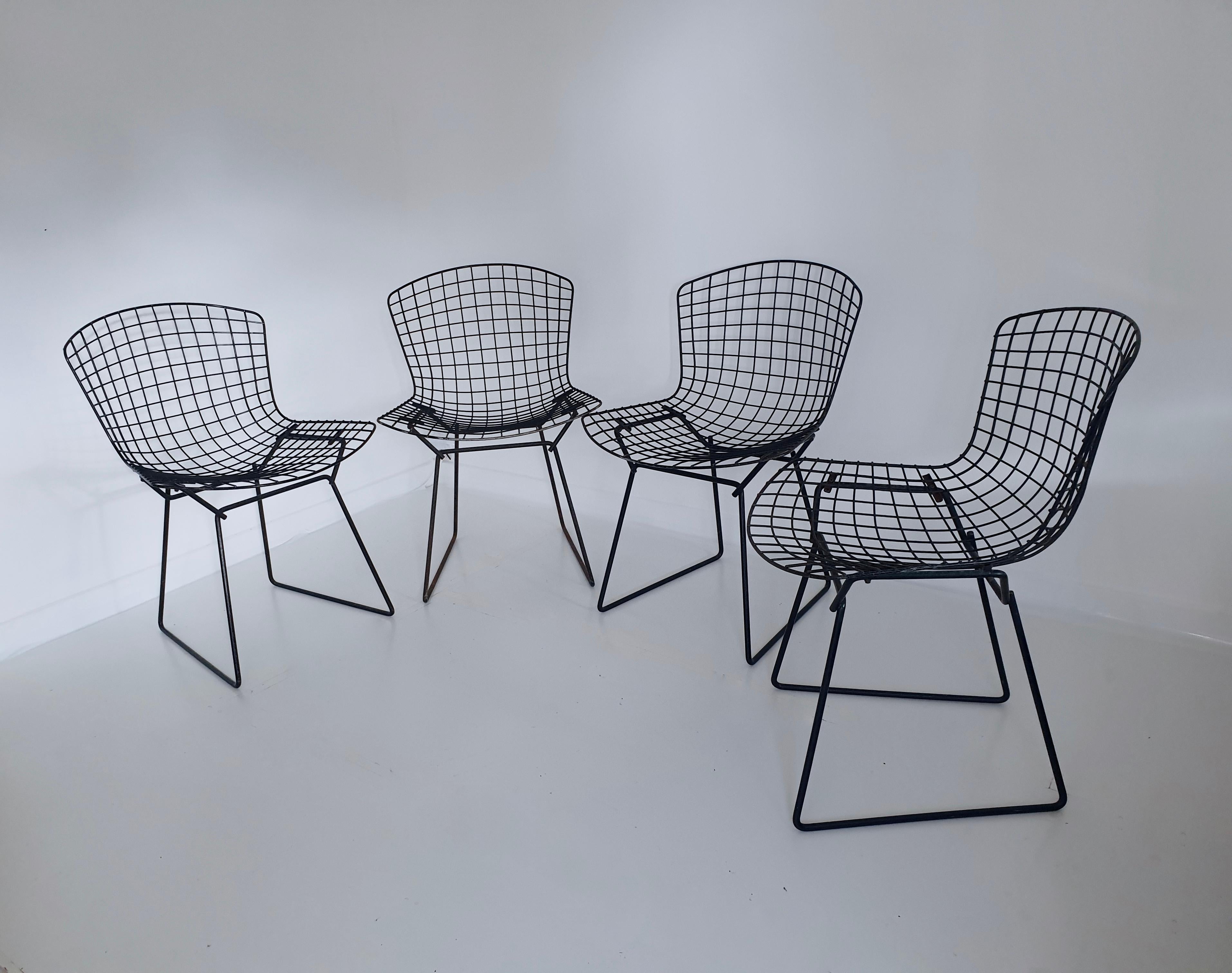 This is a set of 4 early, original production black metal side chairs and seat pads designed by Harry Bertoia for Knoll in the 1950s and produced circa 1960. As early models, made prior to production being moved to Italy, they are formed from a