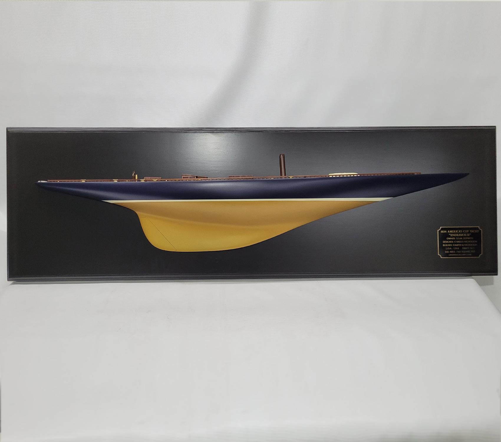 Half model of the America’s cup Yacht Endeavor. This is a 4-foot hull mounted to a blackboard. The Hull is painted blue over gold. The planked deck has skylights, Companionway, Spinnaker pole, Lifeboat, Cleats, Toe rail, Etc. Mounted to a varnished