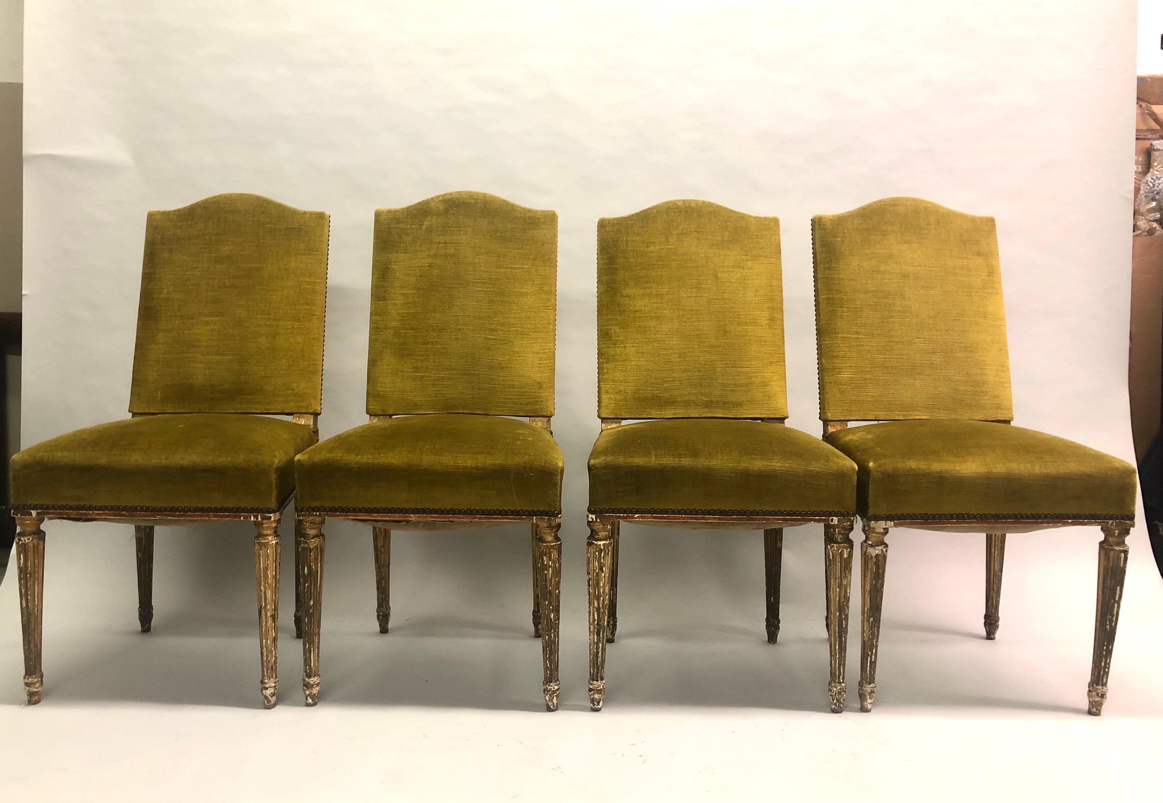An elegant set of 4 French midcentury / 1940s dining chairs in the modern neoclassical style attributed to Maison Jansen. The chairs feature a sensuous form with fluted legs that are partially gilt and sculpted chair backs.