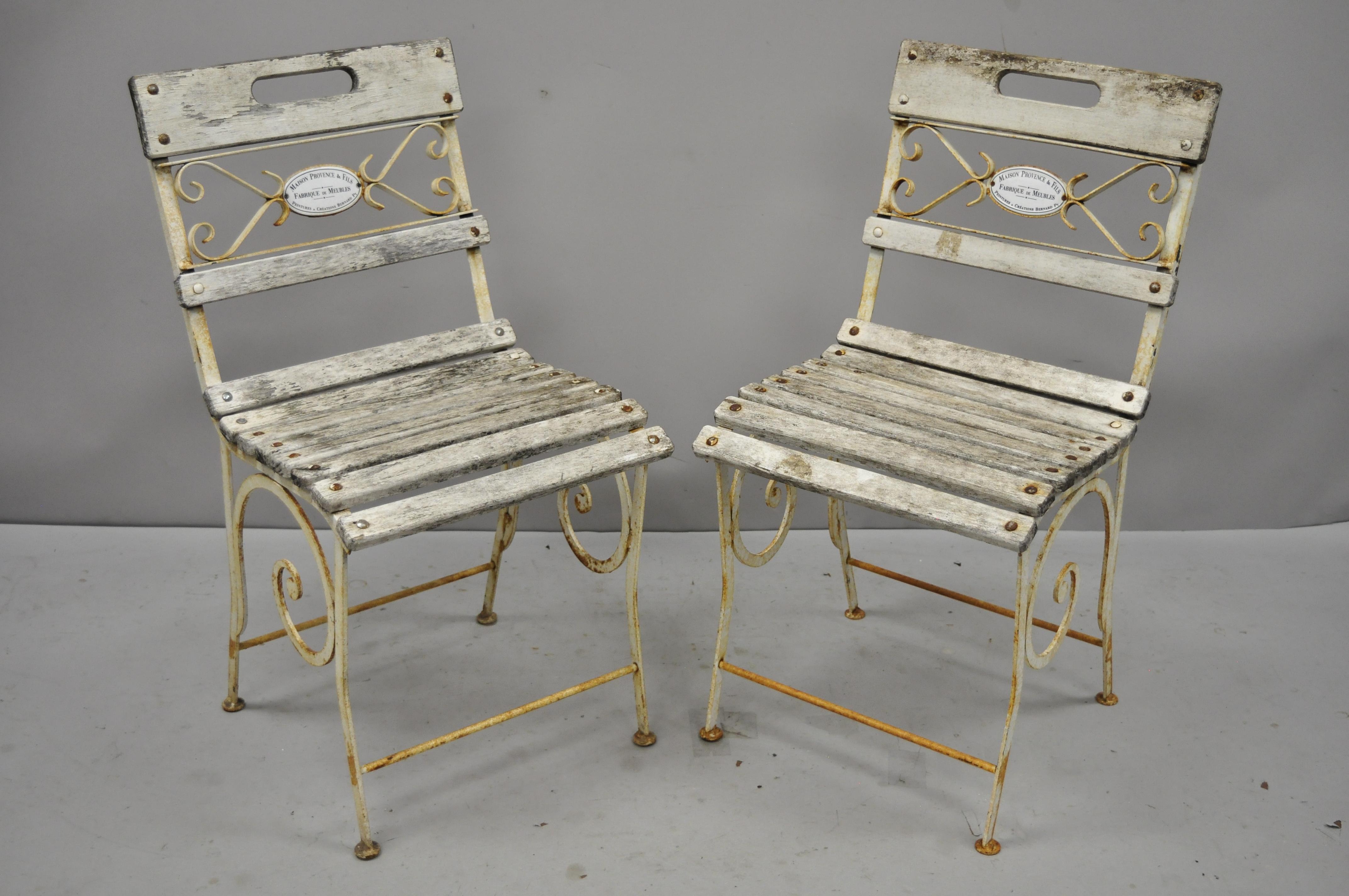 Set of four vintage French Victorian wrought iron and wooden slat seat patio side chairs by Maison Provence & Fils. Item features scrolling wrought iron frames, wooden slat seats, porcelain enamel plaque to back which reads 