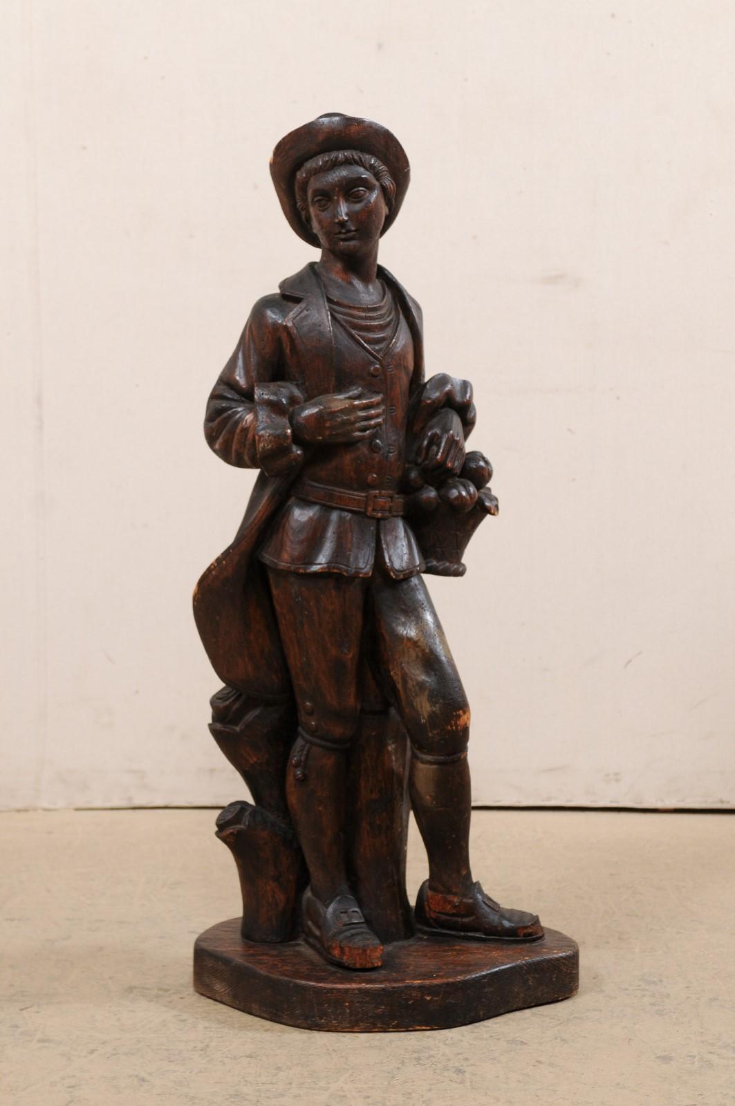An Italian carved wood male figure from the mid 20th century. This vintage carved-wood statue from Italy features a young male figure, dress in 18th century attire (habit à la franchise, which consisted of a jacket, breeches and a vest), standing
