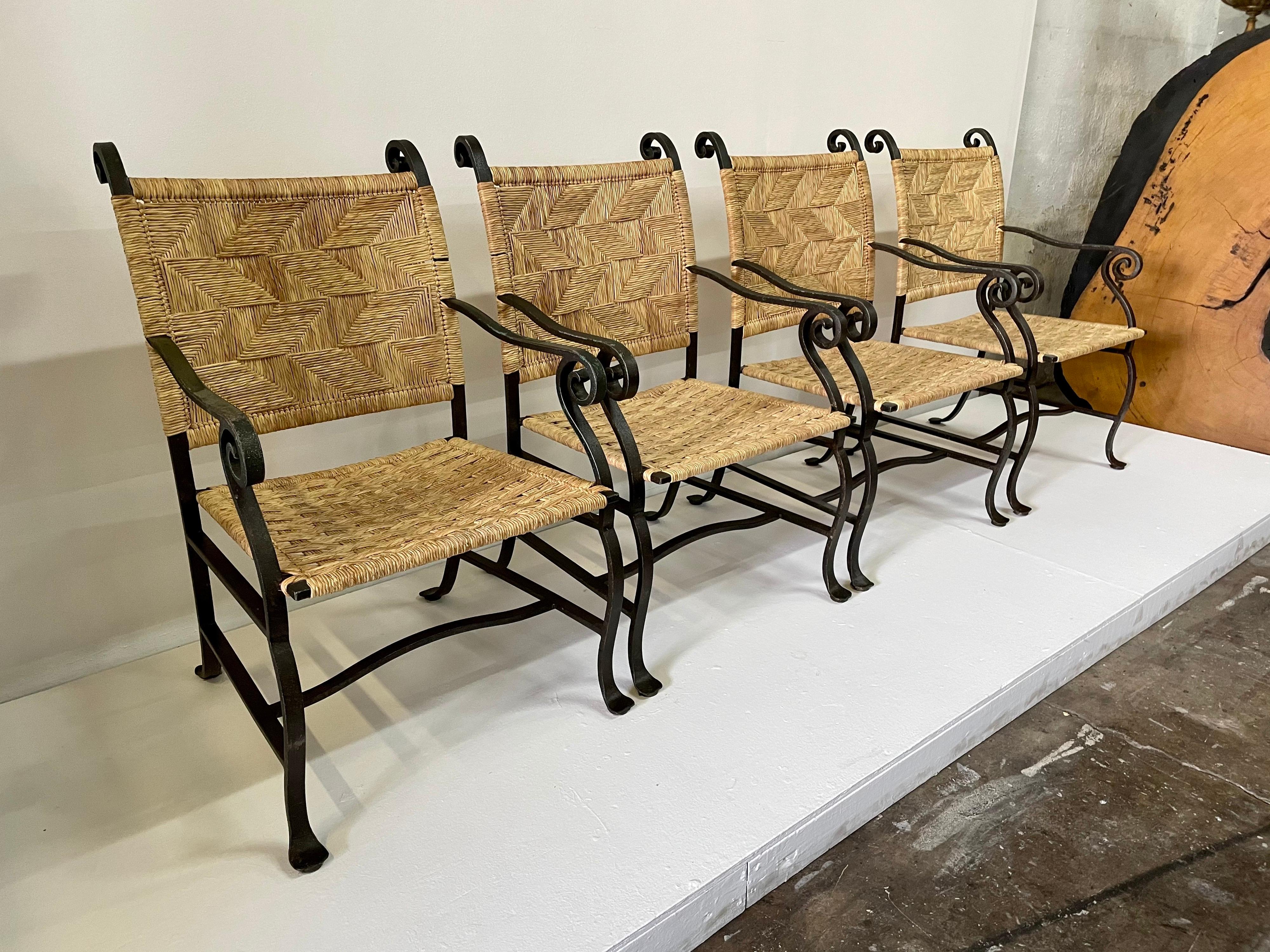 Woven raffia seat and back rests in chevron pattern, these heavy and important hand wrought iron armchairs retain the wonderful original wear and patina from years of use and enjoyment. Made in Mexico, these hand forged iron chairs are heavy and