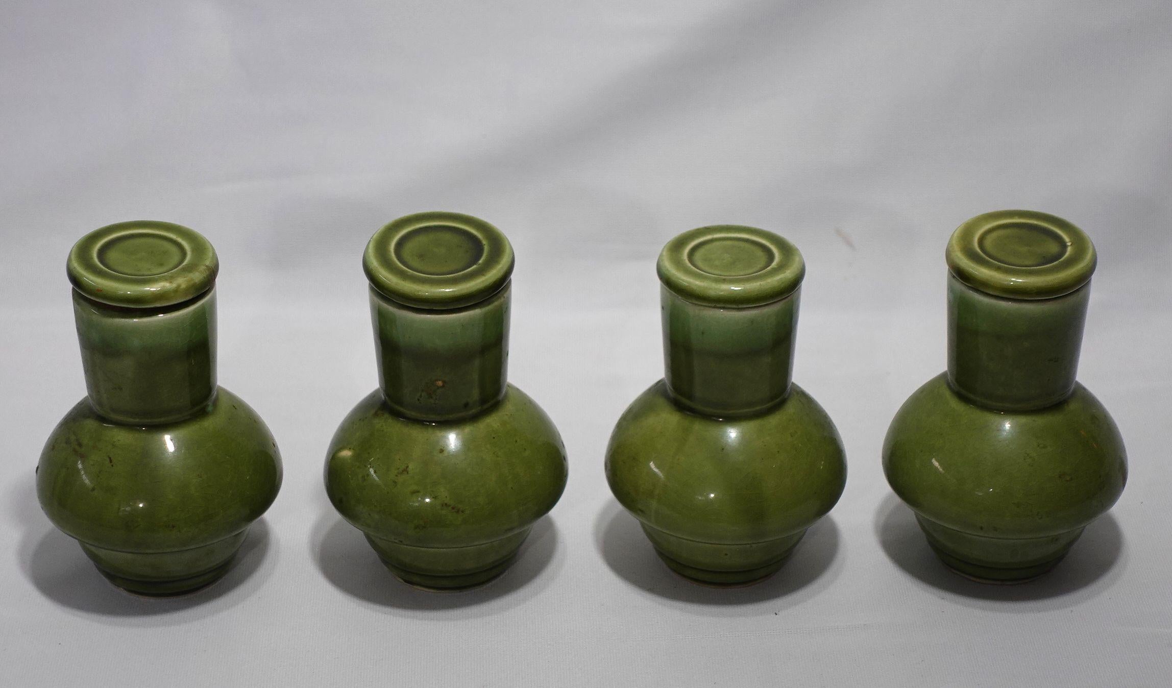 4 Japanese NASCO Porcelain Sake Bottles, Mid-20th century.
Green drip-glazed porcelain with cork-lined stopper. Some of the cork has deteriorated. Label on bottom. Each stands 5.5