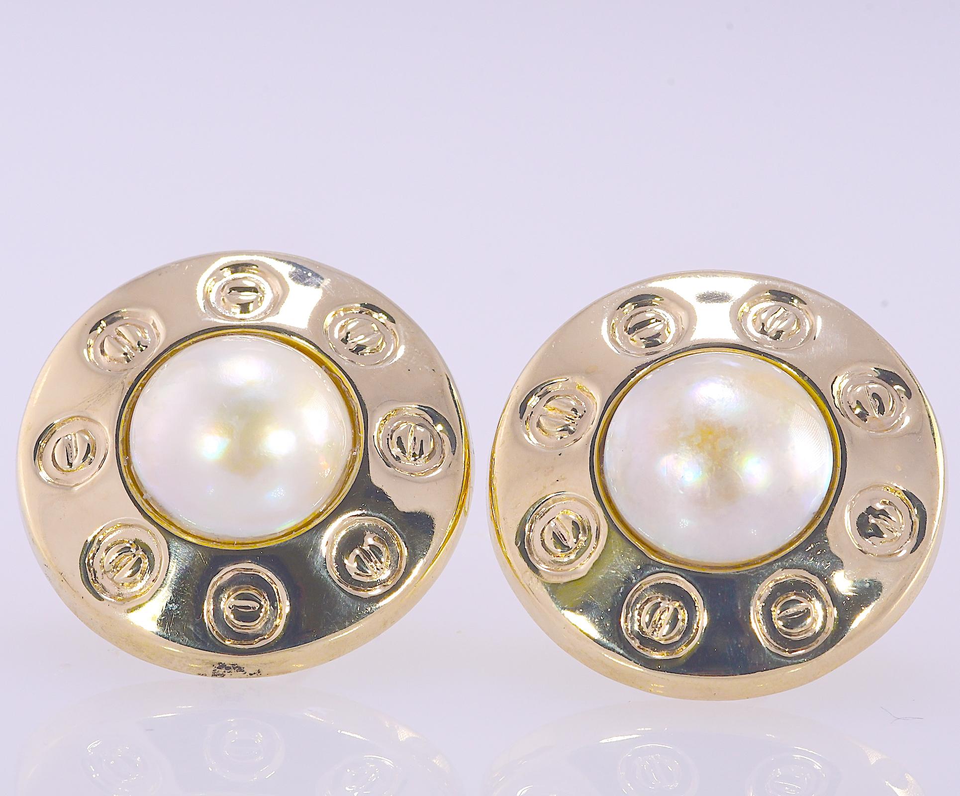 The 15 millimeter round mabe pearls are bordered by a high polished frame with a circular screw pattern resembling the Cartier screws. The overall diameter of the earrings are 1 1/4 inch. The earrings are 14 karat yellow gold and weigh 13.0 grams.