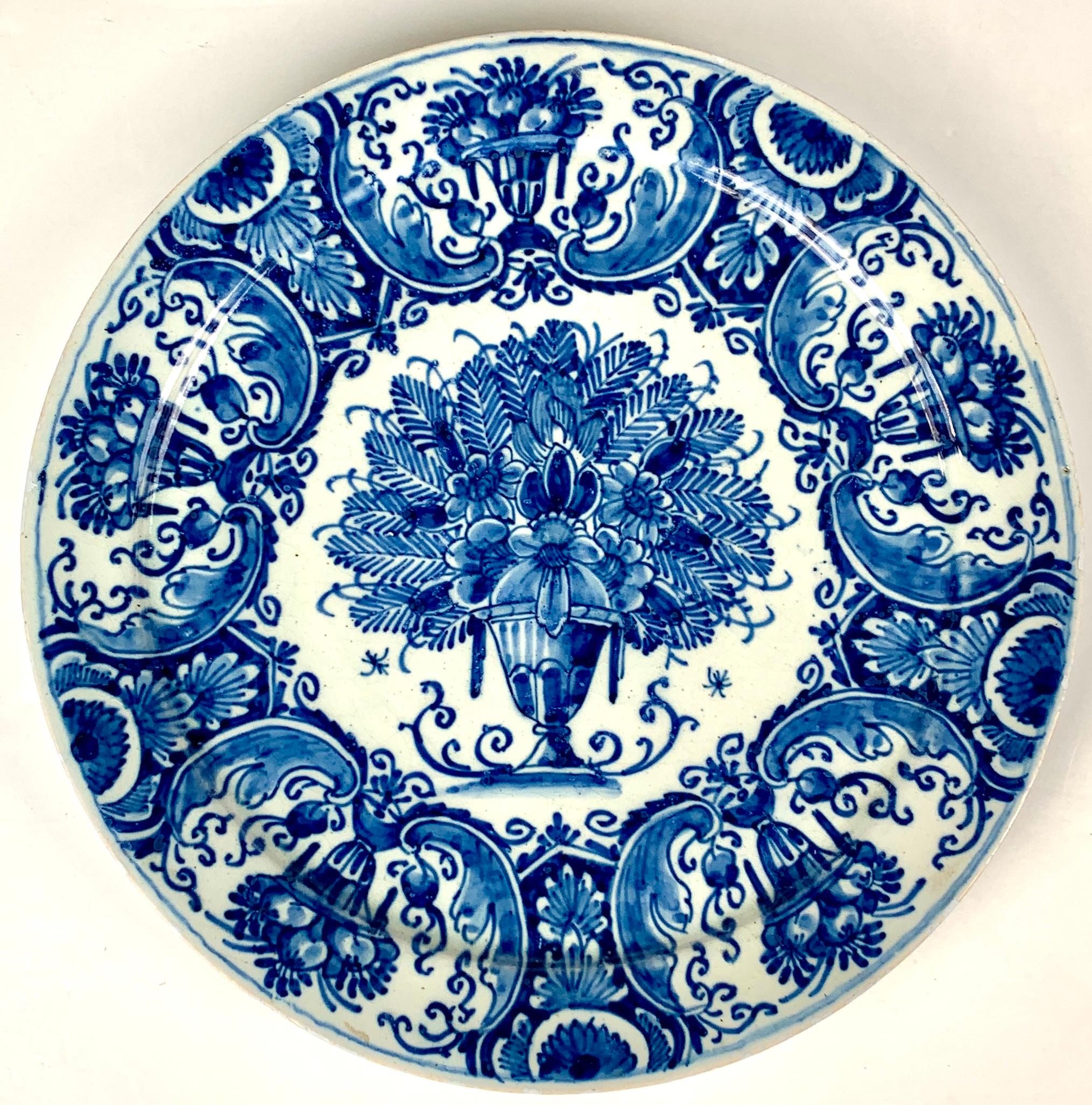 Made in The Netherlands circa 1770, this set of large Dutch Delft blue and white plates is painted in a lovely combination of deep and medium cobalt blue. The central image, a vase overflowing with ferns and summer flowers, is exquisite. 
The wide