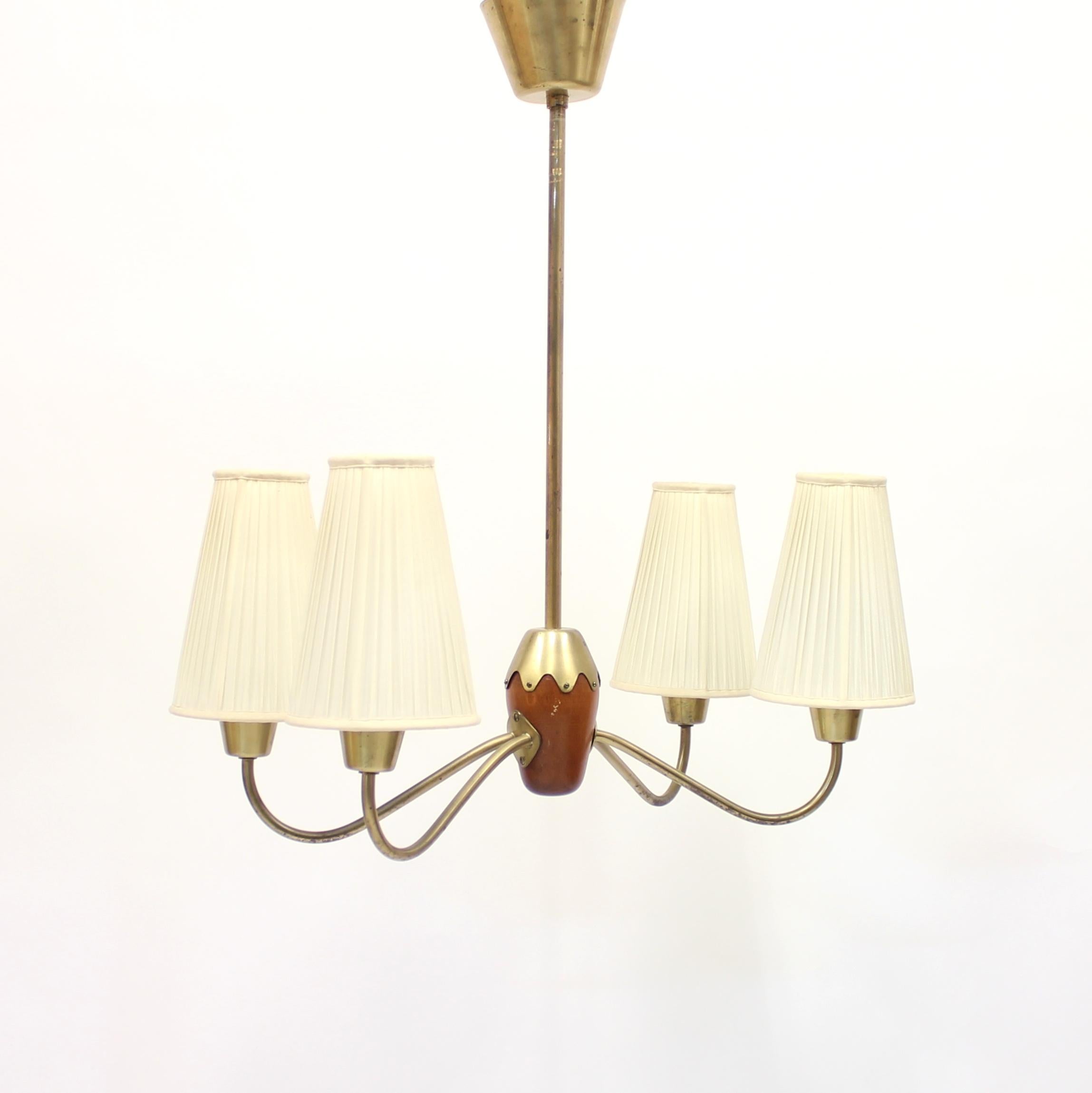 Very unusual brass ceiling lamp with 4 light sources mounted two on each side around a egg shaped mahogany ball with a brass top. 4 pleated shades in off white that most likely are original. Possibly made by ASEA or Ateljé Lyktan. New wiring. Good
