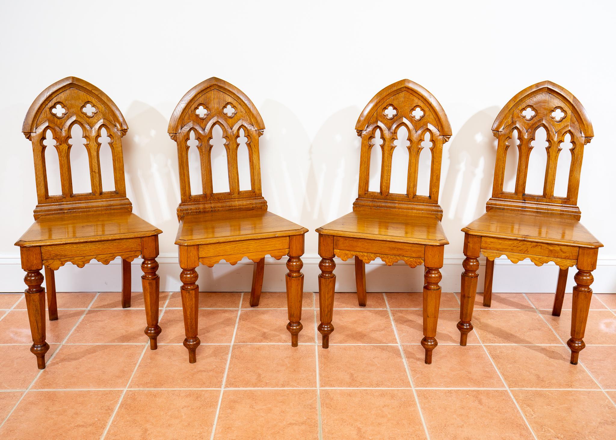 A gorgeous and extremely rare set of 4 Pugin-style gothic golden oak steeple back chairs in wonderful condition. Likely made around the Mid-20th Century, these beautifully crafted and highly decorative chairs make knockout dining or accent chairs