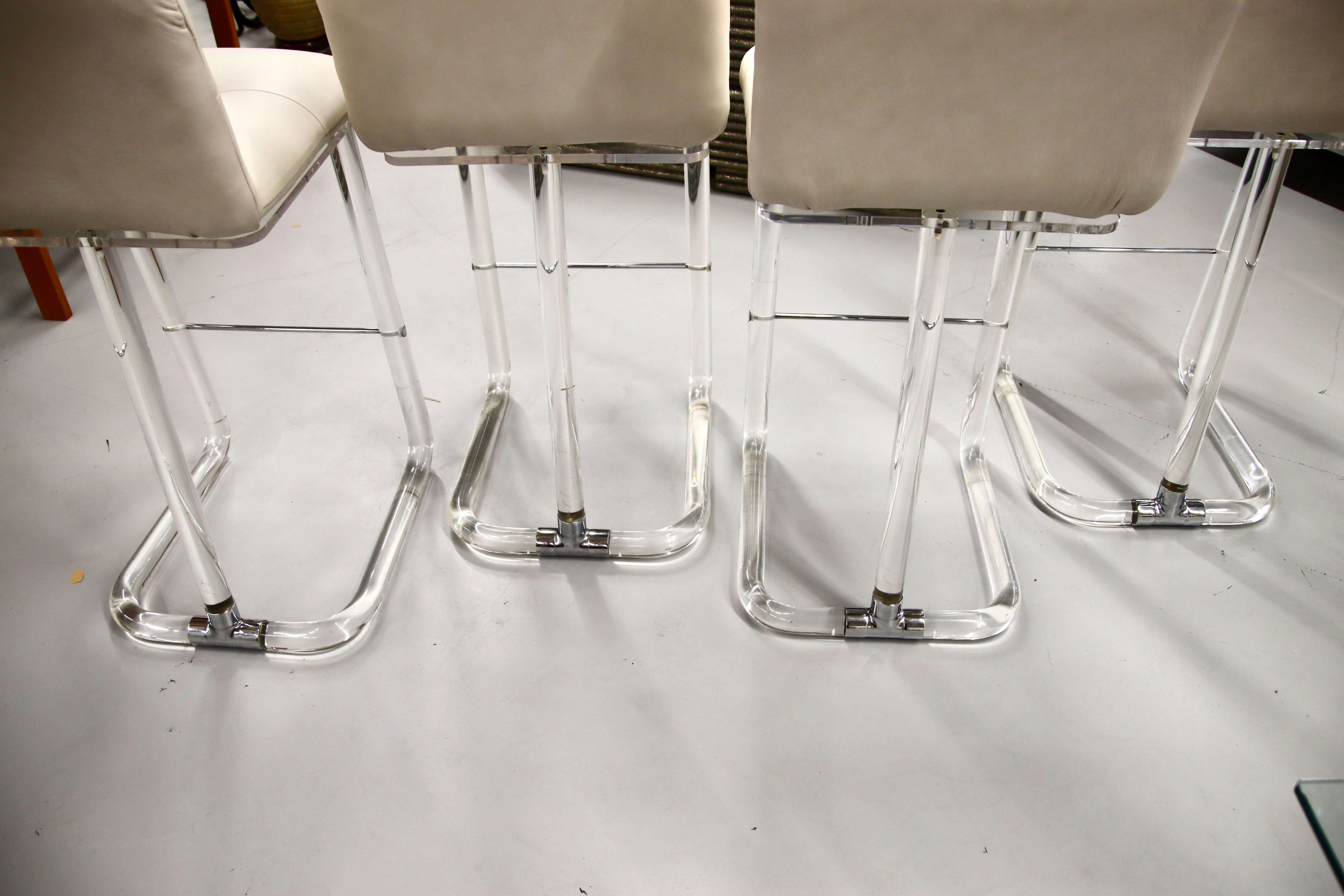 A set of 4 vintage Lucite Lion in Frost bar stools from the 1970s re-upholstered in an Ivory or off-white leather. They swivel as well. In good condition with some minor age and use related marks. Seat height is approximately 30 inches.