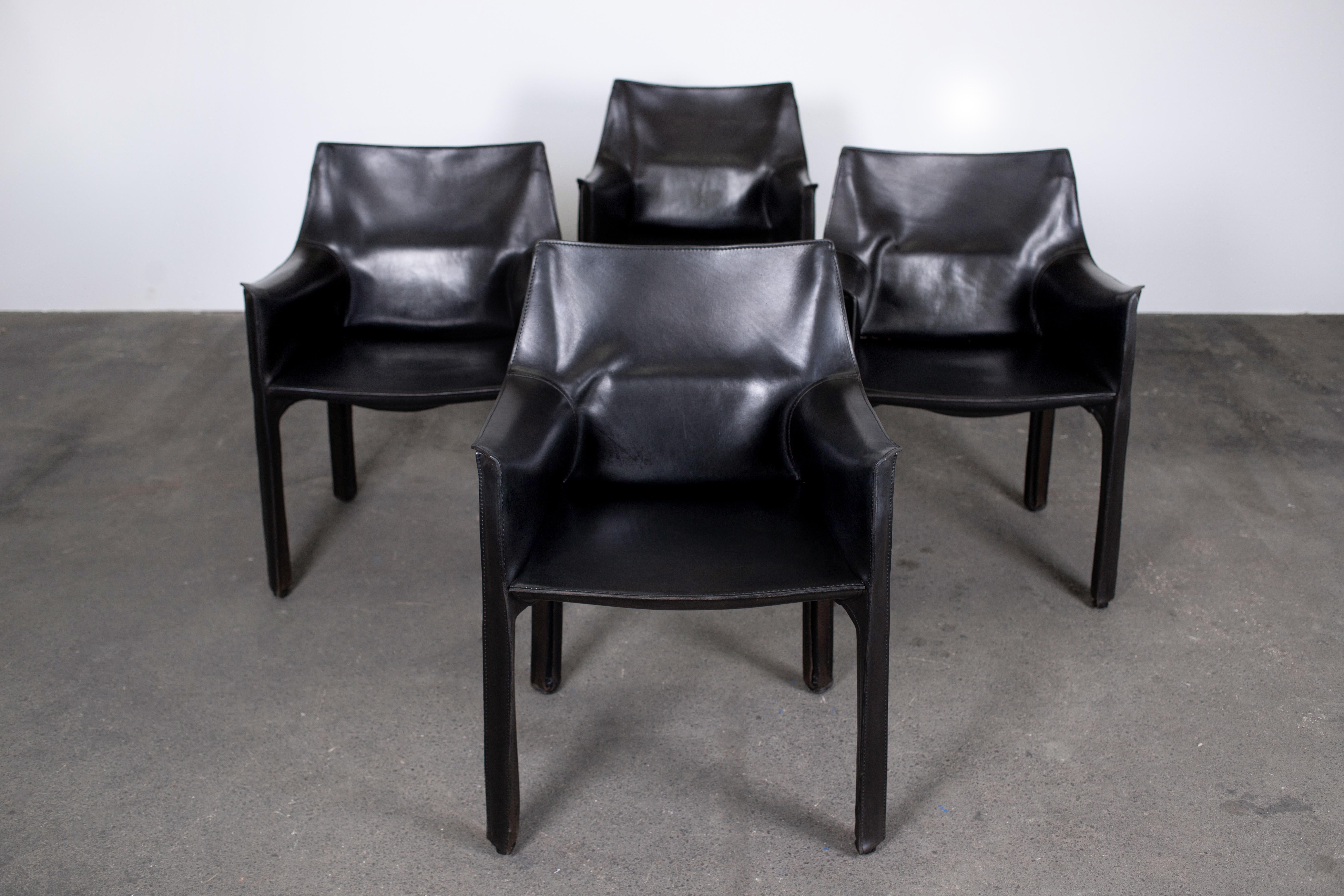 Set of original 4 Mario Bellini CAB 413 chairs, made by Cassina. Flexible steel frame covered with a skin of high quality vintage black saddle leather. The chairs were situated with their backs facing a window for several decades. Consequently, the