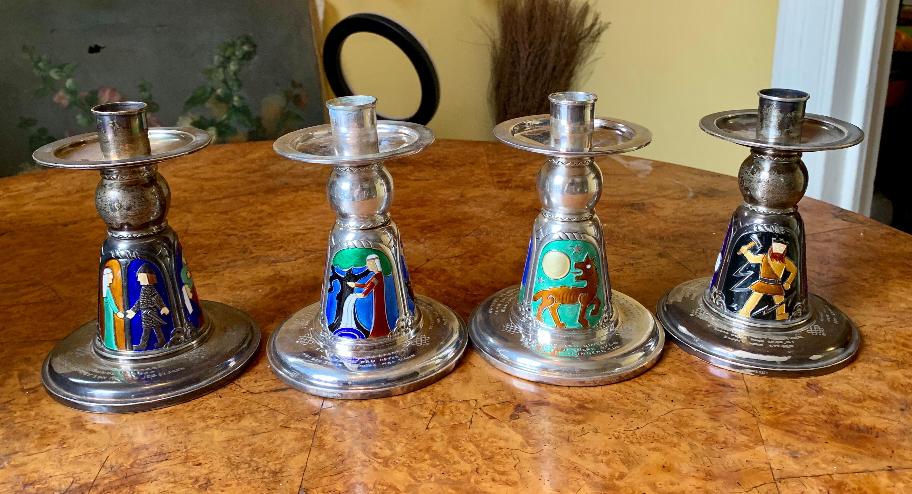 This is a rare museum quality set of Four Norwegian Mid-Century Modernist Enameled Sterling Silver Candlesticks by N.M. Thune of Norway and dating to the 20th century.  Each candlestick is adorned with magnificent enamel images with depictions of
