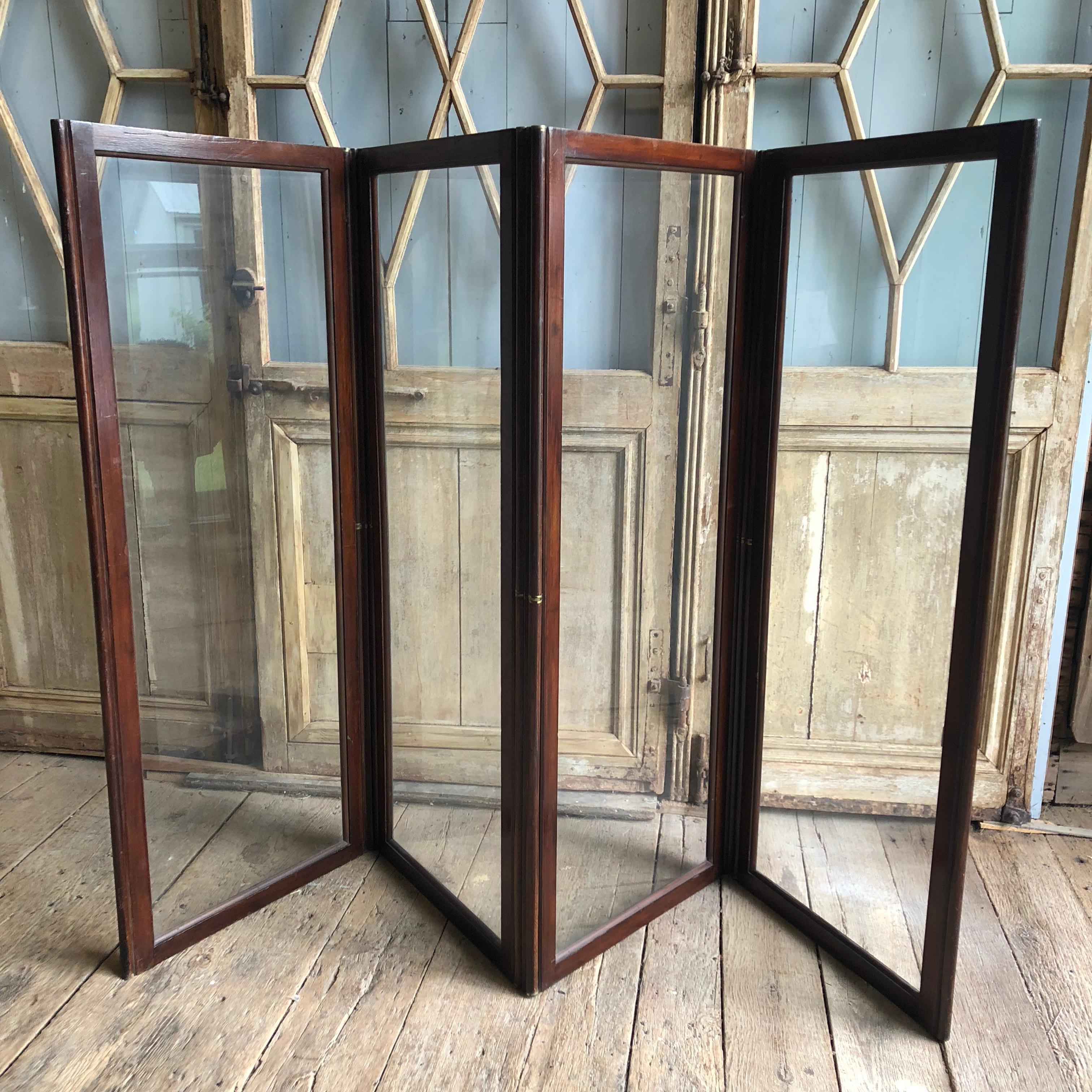 An English 19th century 4-panel folding screen with a brass mounted frame and large glass panels, circa 1850. Each panel is 25.5” wide.