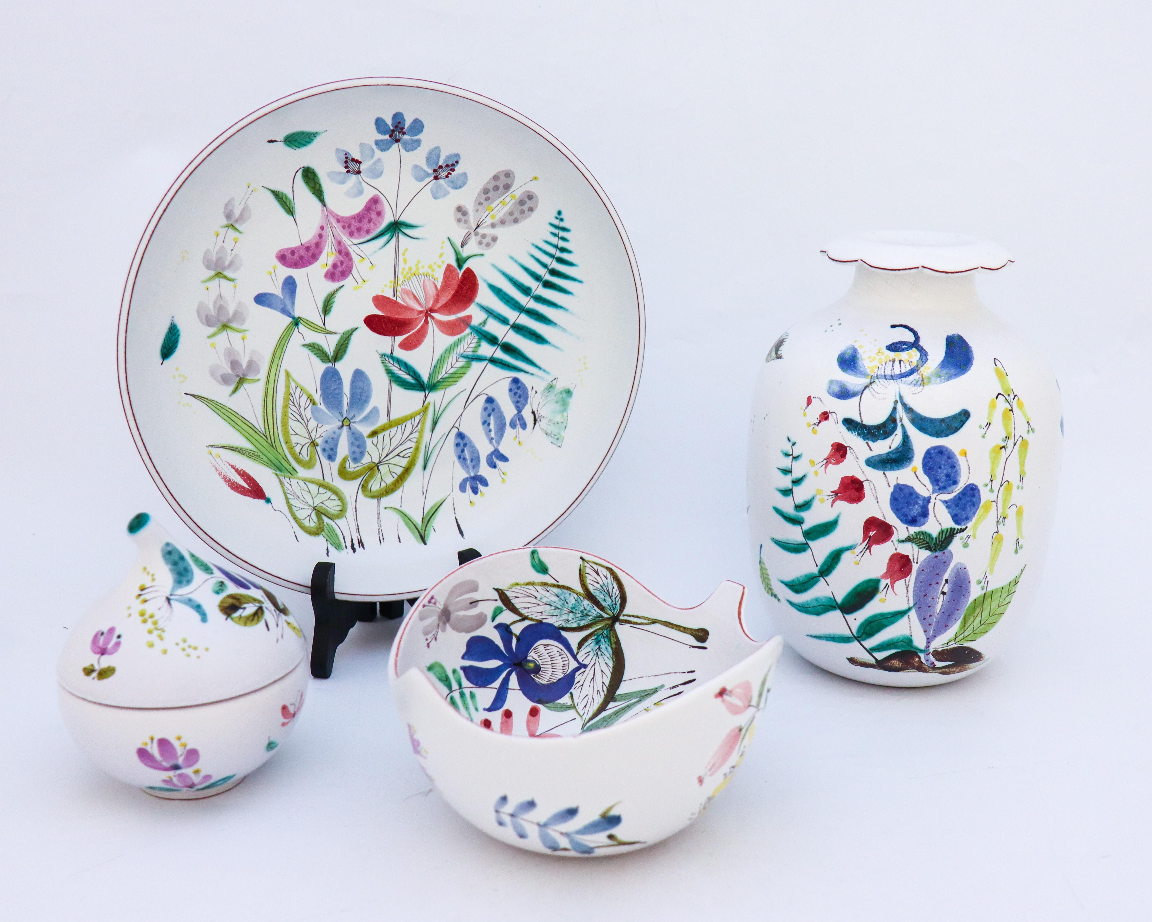 4 faience objects with decor of flowers designed by Stig Lindberg at Gustavsbergs Studio, Sweden. The vase is 21.5 cm high and 14 cm in diameter, the larger bowl is 24.5 cm in diameter and 4.5 cm high. The leaf shaped bowl is 16.5 cm in diameter and