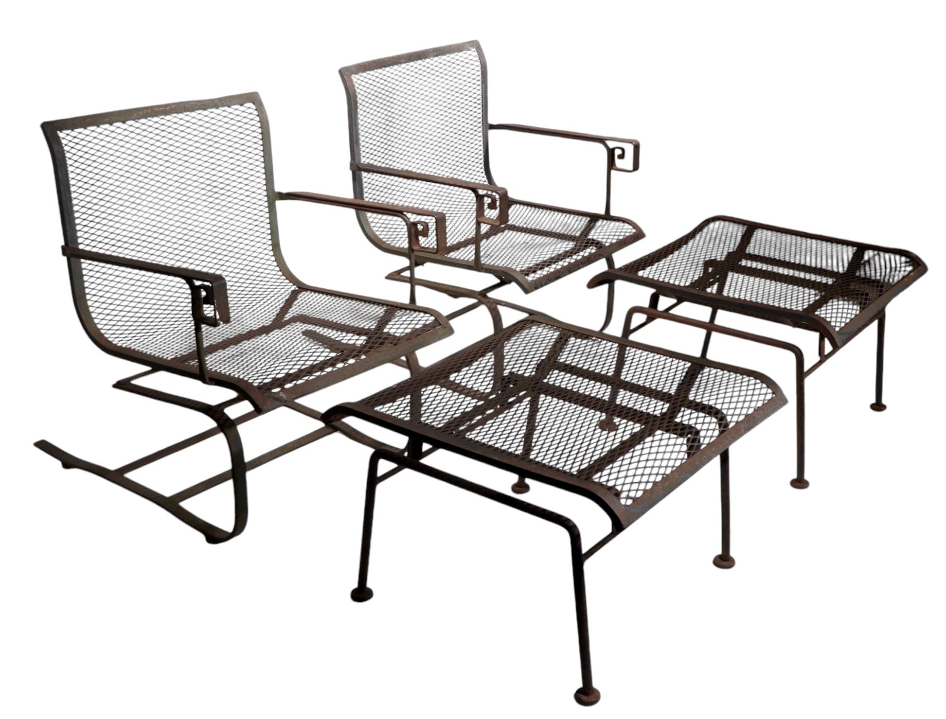 Exceptional pair of cantilevered lounge chairs with original matching footrest, ottomans. The chairs feature iron strap frames with decorative Greek, or Roman  key style, hand rests  with metal mesh seats and backs. The ottomans also have wrought