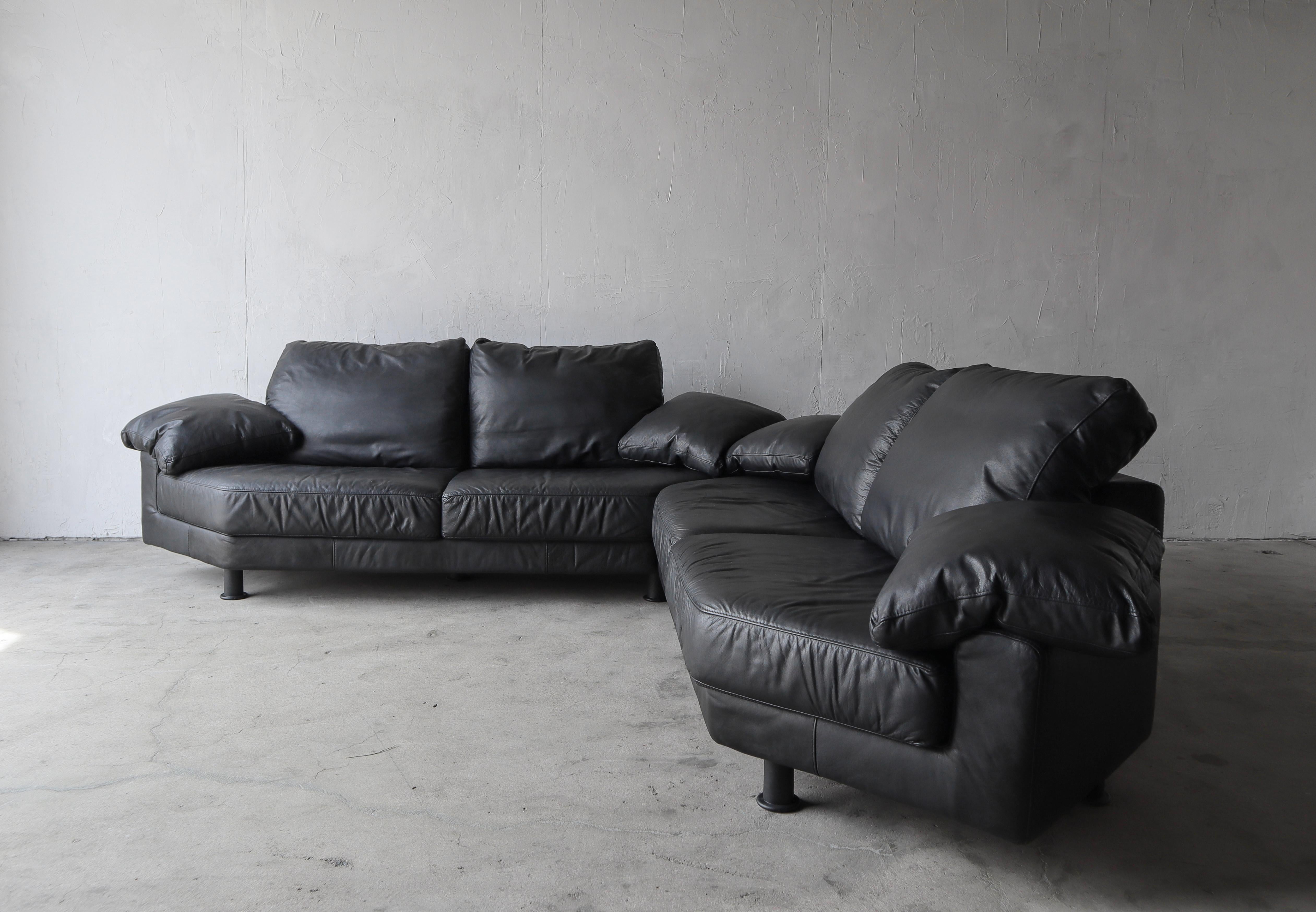 Post modern black italian leather modular sofa, set features 2 identical sofas and 2 ottomans that can be put together in multiple configurations. Can also be used individually as 2 sofas. The sofas have attractive angled edges, adding to the post