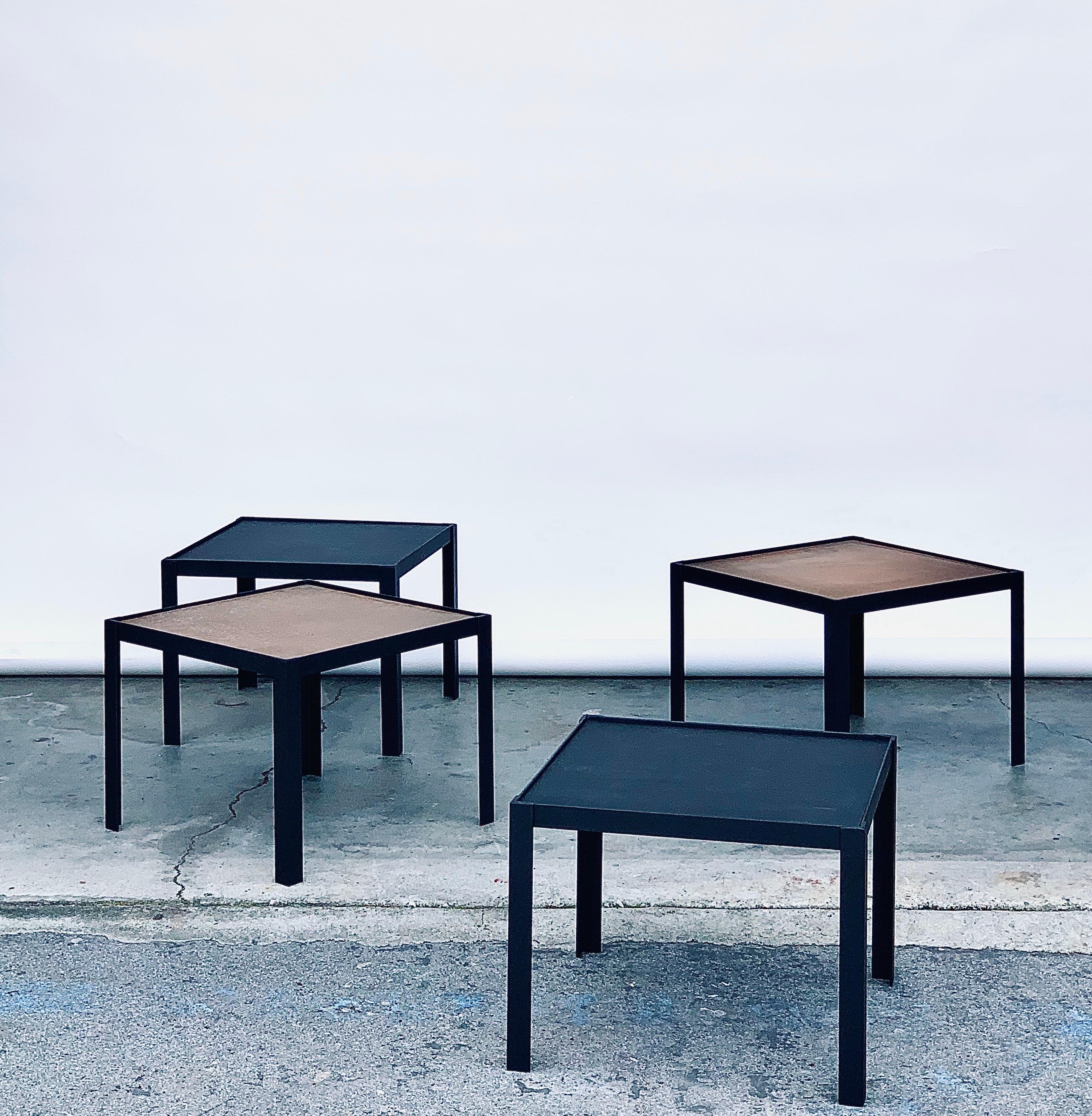Versatile set of 4 'Pion' black leather and patinated brass reversible occasional tables by Design Frères.

Tops are interchangeable between thick matte black leather cutouts and the patinated unlacquered brass panes.

Only sold as a set.