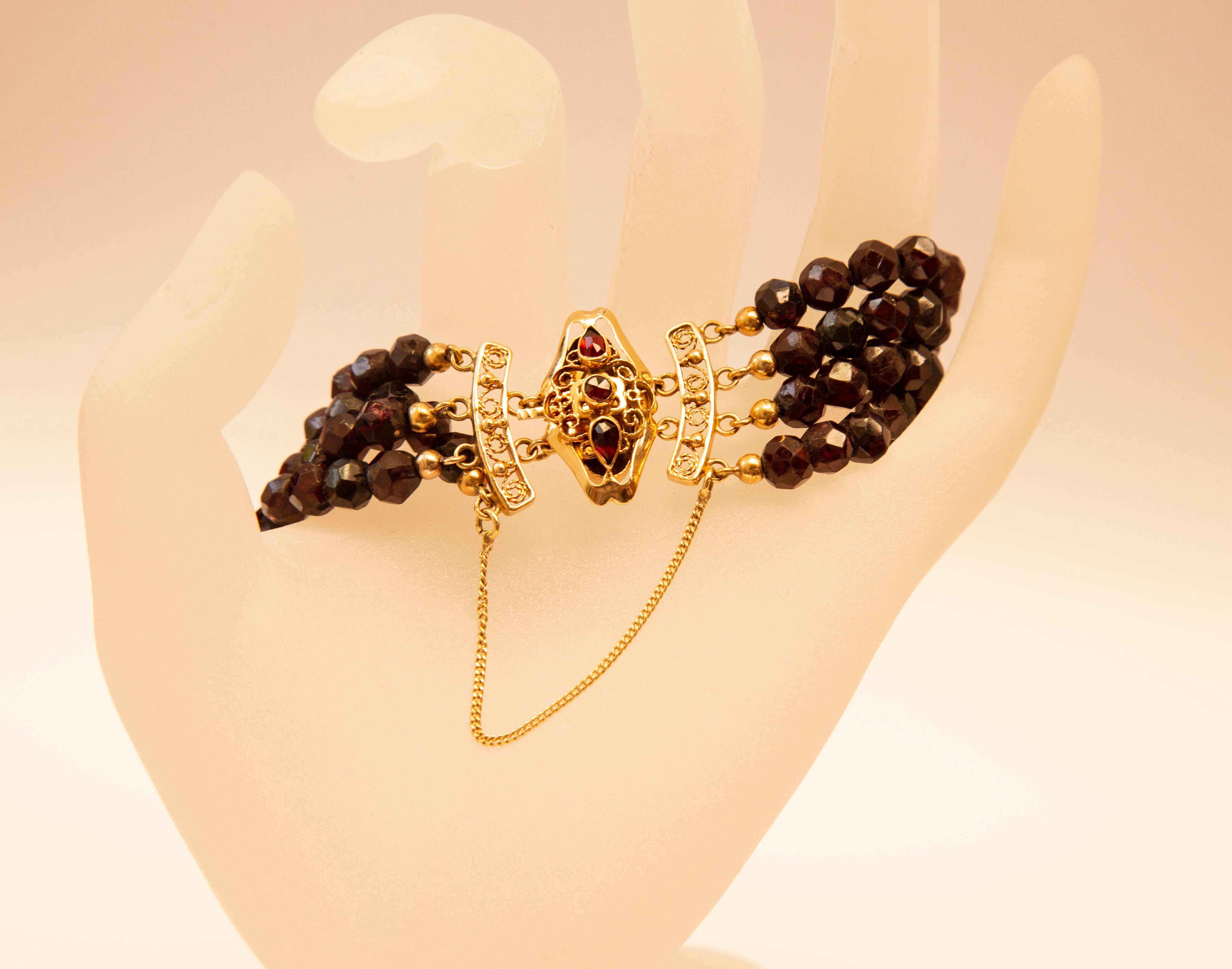 A vintage 4-row genuine faceted garnet beads bracelet with filigree 14 karat solid yellow gold closure. The closure features a 14 karat gold safety chain permanently attached on both sides. The closure is stamped with an oak leaf, that stands for