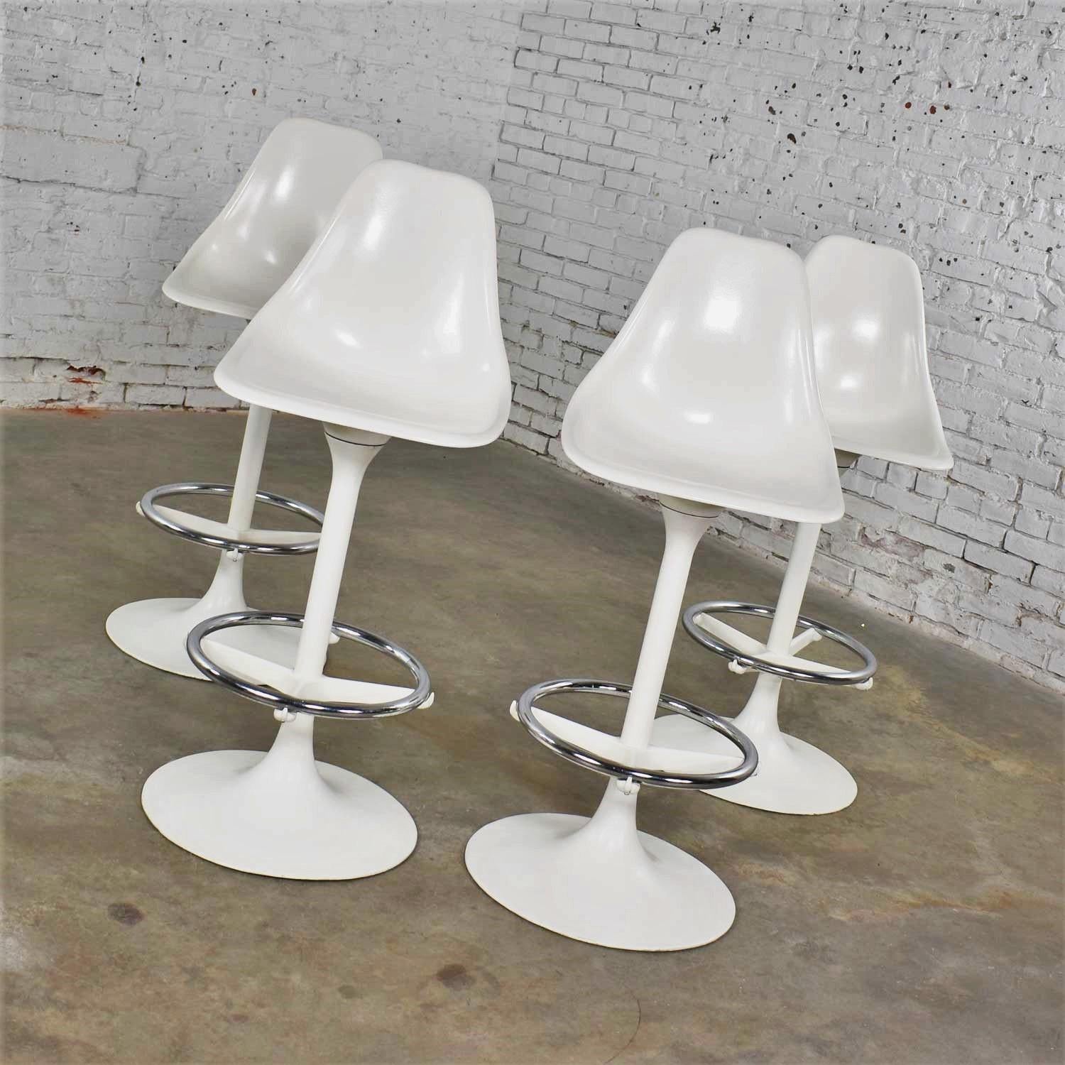 Handsome set of four tulip style white fiberglass and cast aluminum swivel barstools designed by Arthur Umanoff for Contemporary shells. These are bar height stools with a 30-inch seat height. They are in wonderful vintage condition. We believe the