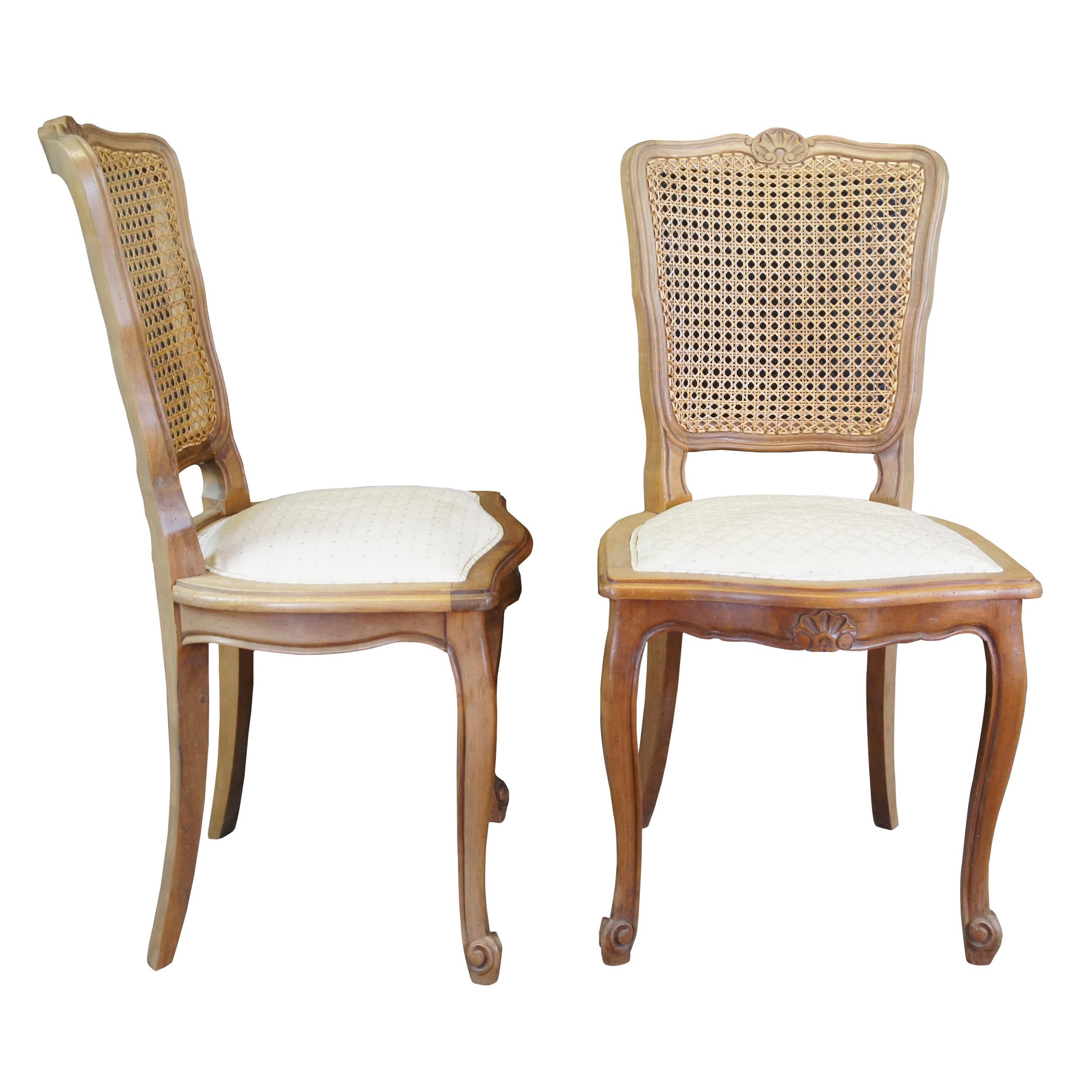 Tricoire vintage French Country dining chairs, circa 1980s. Made from naturally distressed solid walnut with a serpentine scalloped crest rail, contoured stiles, cane back and upholstered seat. The chairs are supported by cabriole legs along the