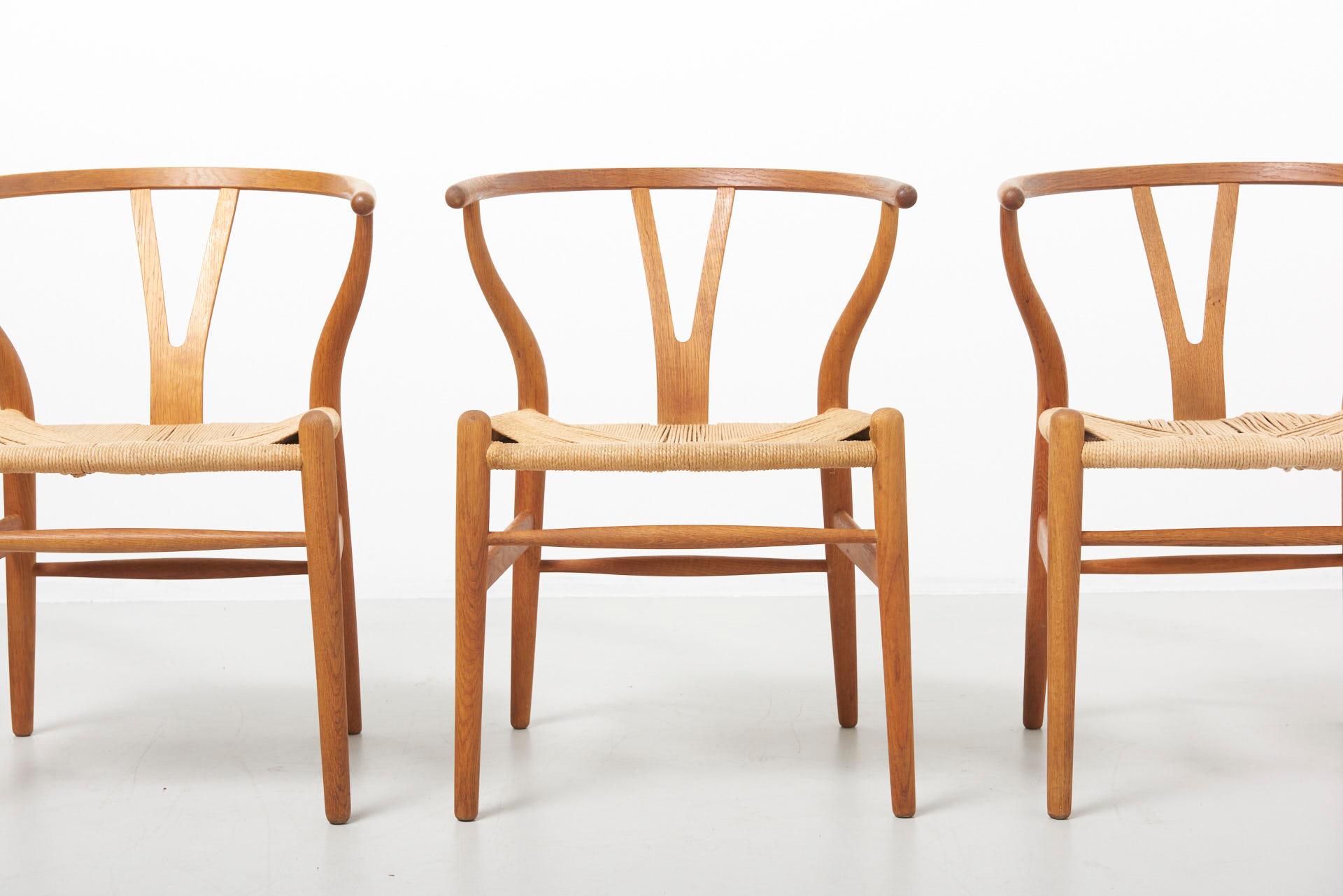 A set of 4 dining chairs in soap treated oak with paper cord seats, known as the Wishbone chair. Design by Hans J. Wegner in 1950. Model CH24, made by Carl Hansen in Denmark. These chairs were made in 1997.