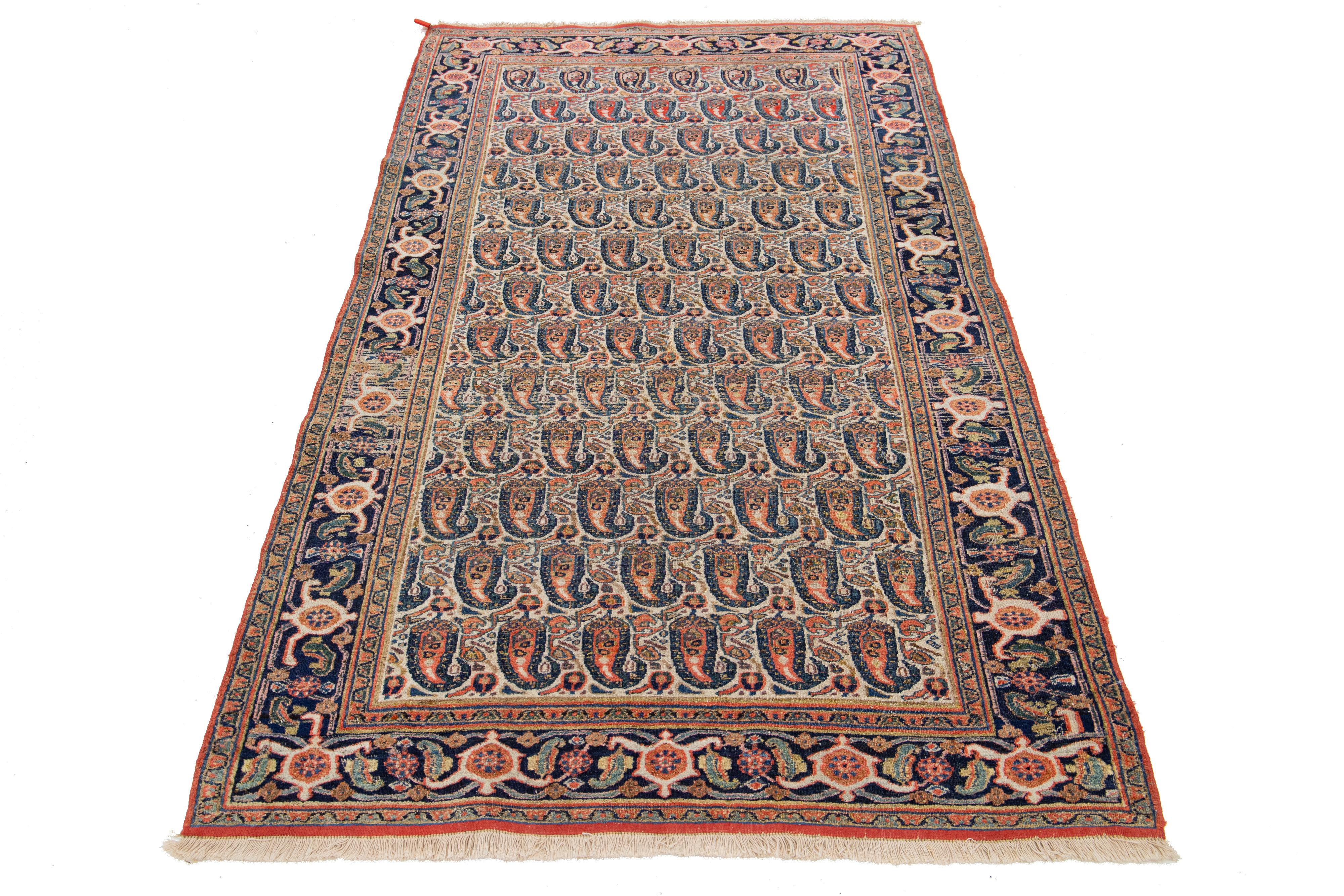 Dies ist ein handgeknüpfter persischer Malayer-Teppich aus dem 20. Jahrhundert. Es hat ein beiges Feld mit orangefarbenen und blauen Akzenten im Boteh-Muster.

Dieser Teppich misst 3'9