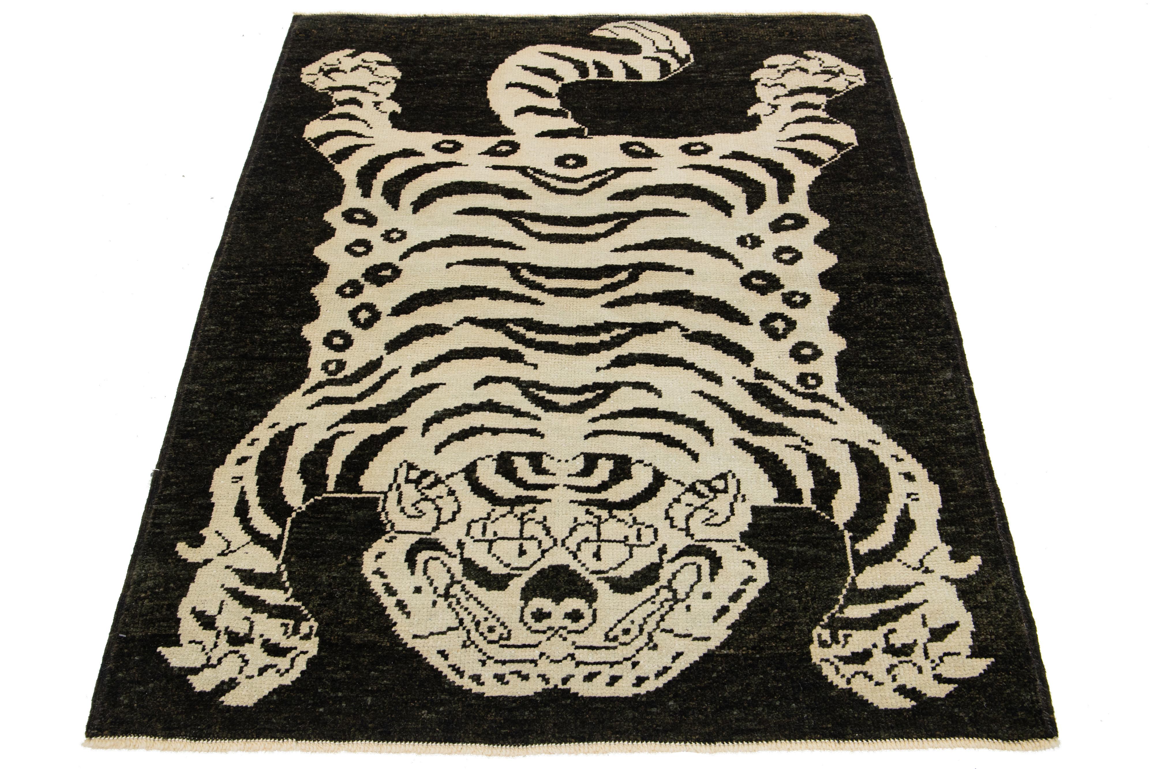 This Turkish Art Deco wool rug boasts a striking black backdrop with beige accents and a captivating pictorial representation of a tiger.

This rug measures 4'4