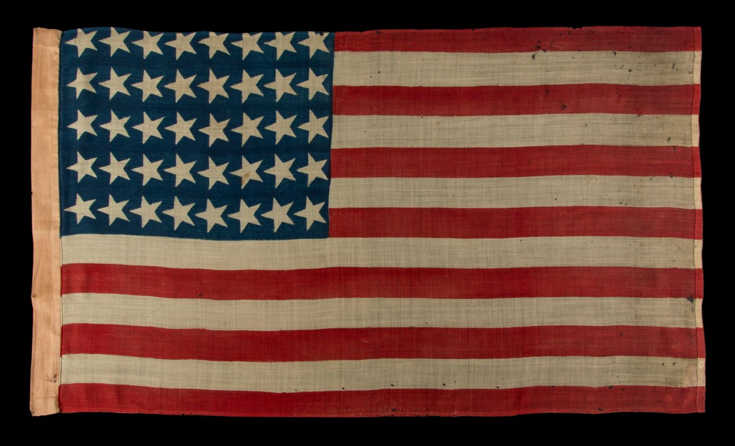 40 CANTED STARS IN AN ORDERLY PHALANX, ON AN ANTIQUE AMERICAN FLAG WITH A RARE STAR COUNT, ACCURATE FOR JUST SIX DAYS AND NEVER OFFICIAL, REFLECTING SOUTH DAKOTA'S ADMISSION TO THE UNION:

40 star American national flag, clamp-dyed on wool bunting,