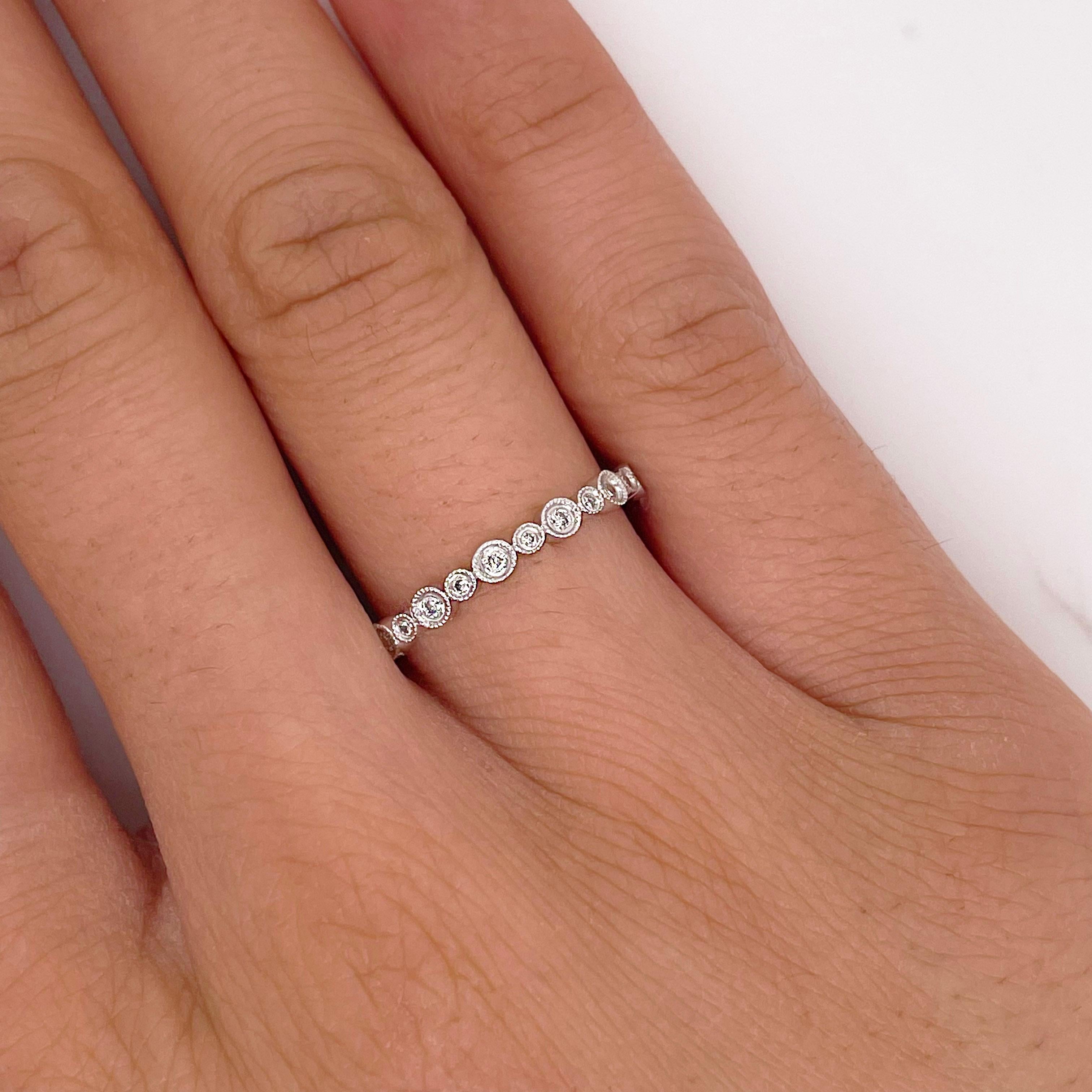 This is a diamond bezel eternity band with a unique design and bold, modern fashion look! This diamond band has round brilliant diamonds going all the way around the ring in an eternity band design. The diamonds alternate in bezel sizes giving the