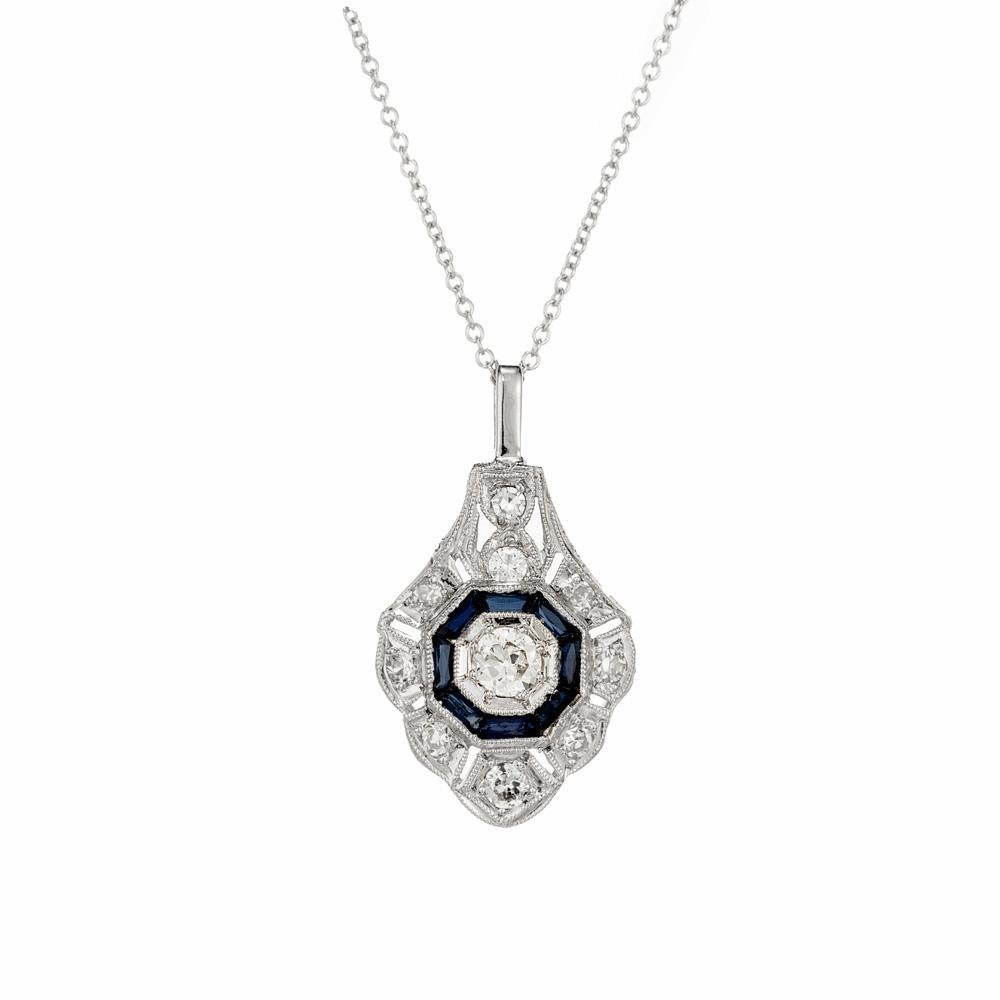 1930's Art Deco diamond and sapphire pendant necklace. One round cut diamond with a halo of 8 French cut baguette sapphires in a 14k white gold open work and beaded setting. Accented with 9 additional round cut diamonds. 18 inch chain. Perfect