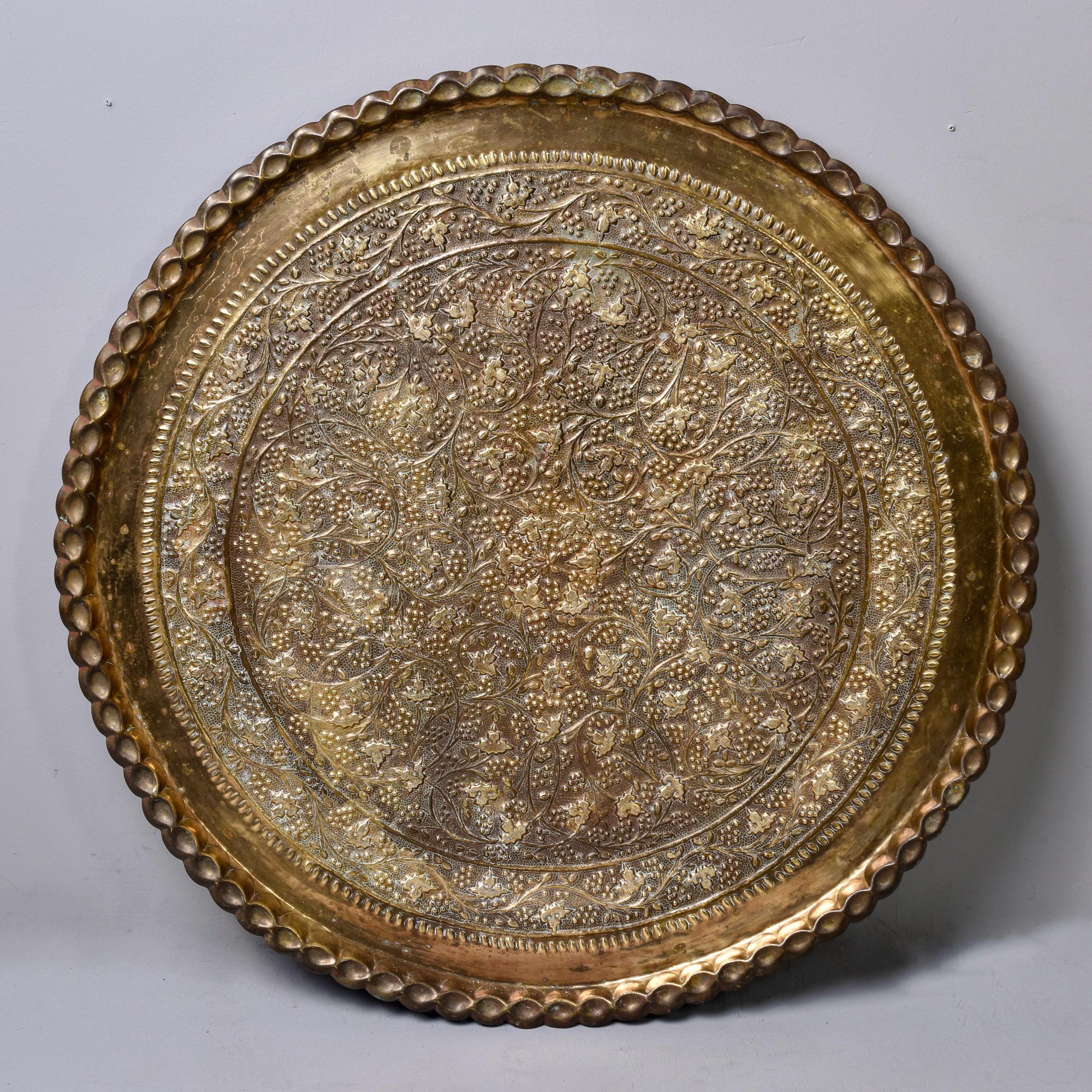 Extra large circa 1950s round Moroccan brass tray with repousse foliate design and scalloped edge. Can be used as a large tray, wall decoration or tabletop on a base. Unknown maker. Measures: 40” diameter.
  