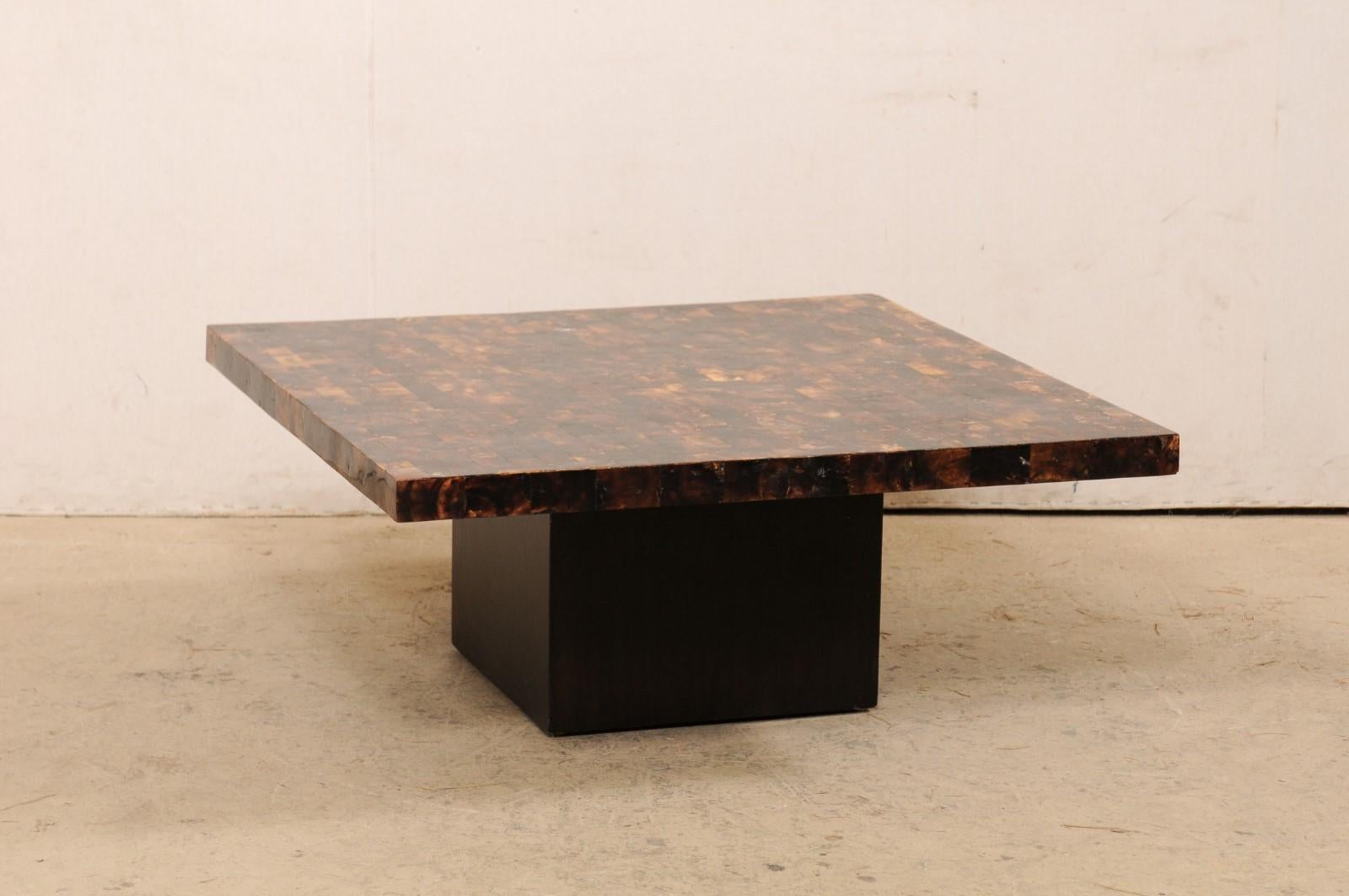 A vintage American acrylic-top coffee table. This square-shaped coffee table has a black and brown colored brick-pattern acrylic top, designed in straight/clean lines, which is raised upon a black wooden block-style pedestal base. This 40