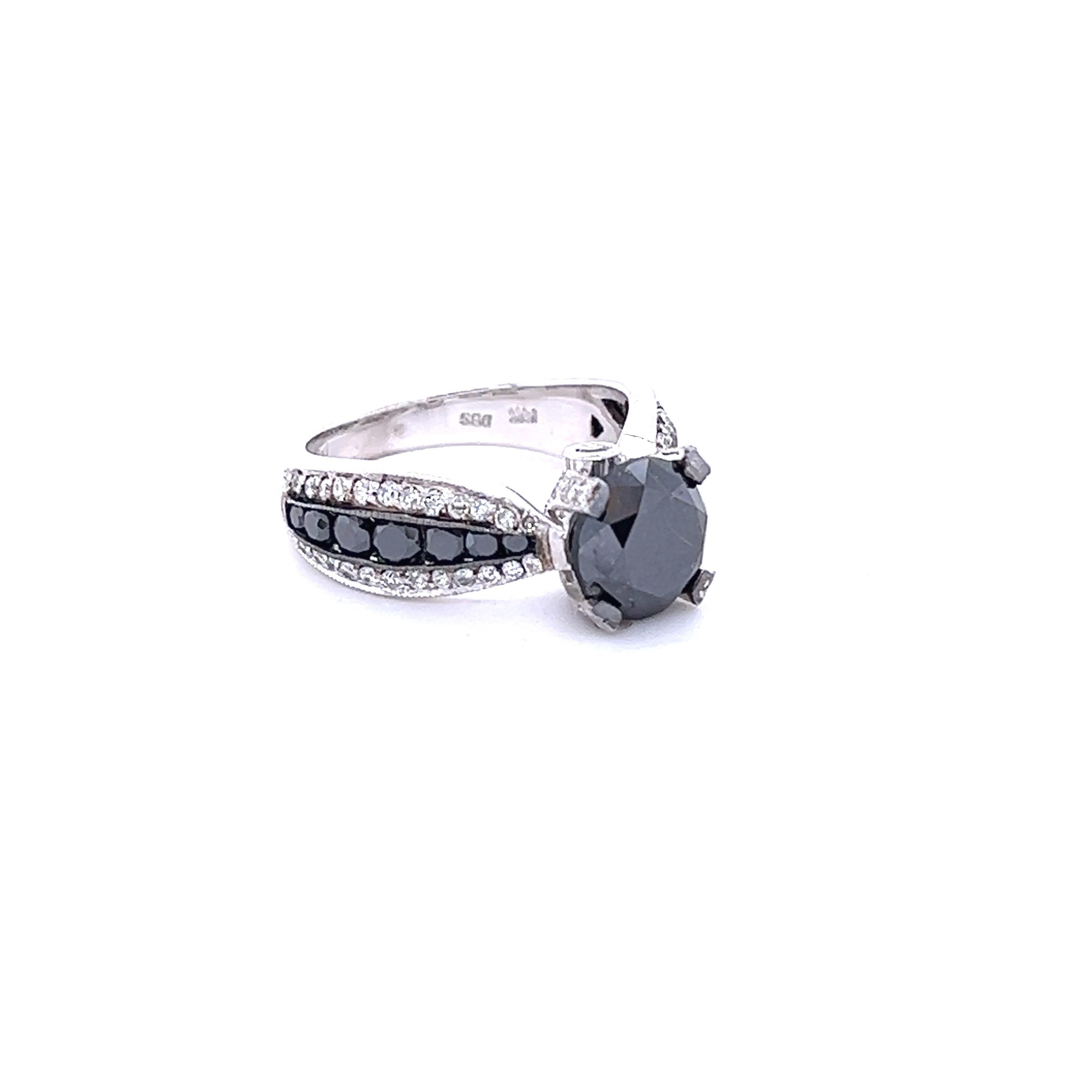 The Round Cut Black Diamond is 2.77 Carats and measures at approximately 8 mm. The setting has 14 Black Round Cut Diamonds weighing 0.71 Carats and 66 Round Cut Diamonds that weigh 0.52 Carats. (Clarity: SI, Color: F) The total carat weight of the
