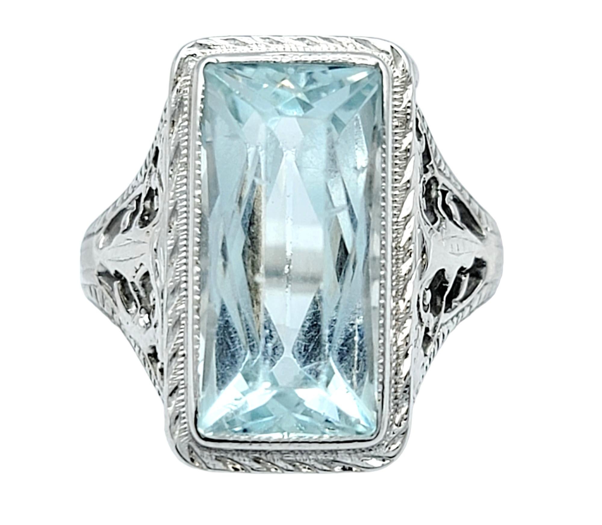 Ring Size: 6

This vintage cocktail ring, set in lustrous 18 karat white gold, is a true testament to timeless elegance and sophisticated design. At its heart lies a mesmerizing 4-carat baguette-cut aquamarine gemstone, beautifully bezel-set. The