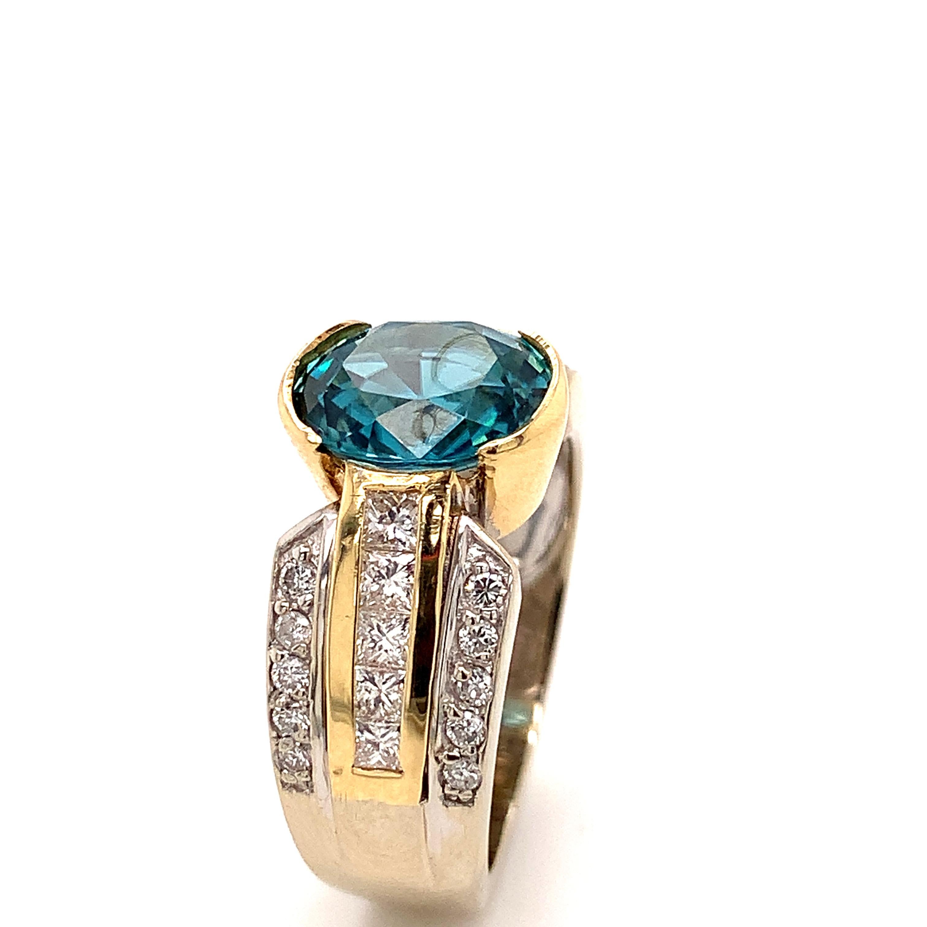 Blue Zircon and Diamond two tone cocktail ring.
This oval blue Zircon center stone, cut in Cambodia, weighs 4.01 carats and is semi bezel set.
There is a total of 30 Diamonds in this sturdy 14-karat two tone Diamond ring. 20 round 0.44 carats  and