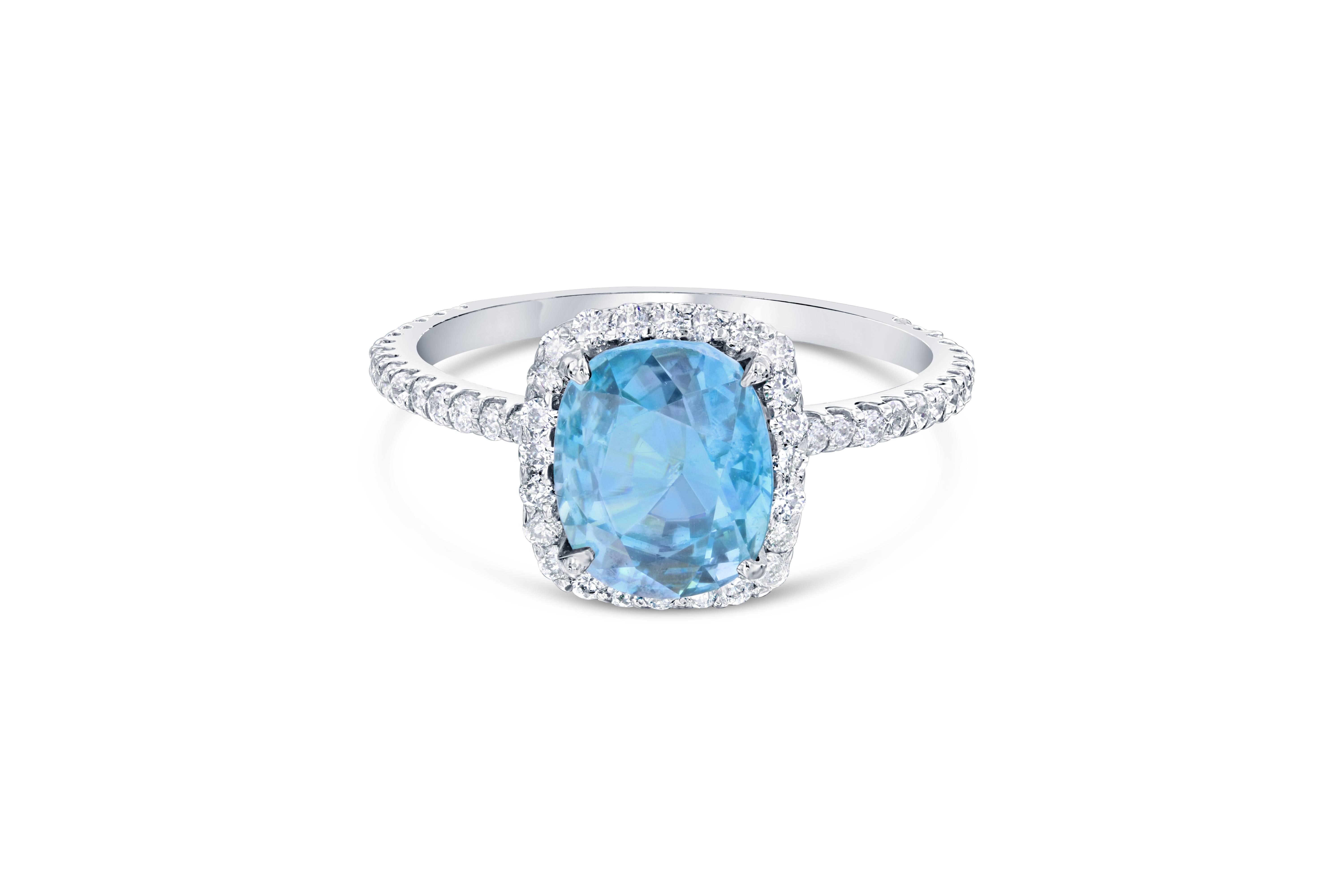 A Dazzling Blue Zircon and Diamond Ring! Blue Zircon is a natural stone mined in different parts of the world, mainly Sri Lanka, Myanmar, and Australia. 

This Cushion Cut Blue Zircon is 3.45 Carats surrounded by a simple halo and shank of 68 Round