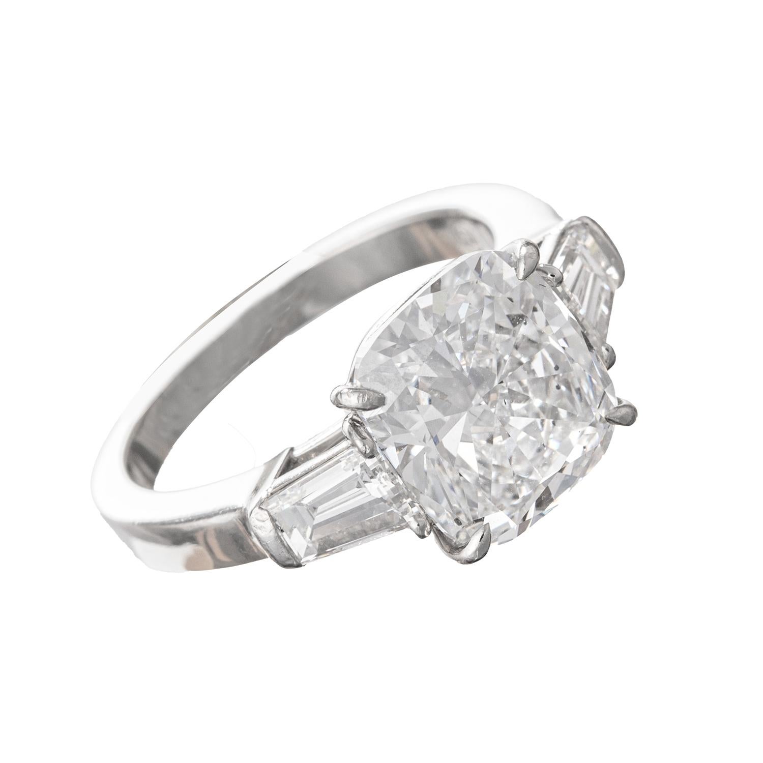 Handmade diamond engagement ring in platinum, centering a colorless cushion brilliant-cut diamond weighing 4.01 carats (E-color, SI2-clarity) flanked by tapered baguette-cut diamond side stones.  Two tapered baguette-cut diamonds weighing