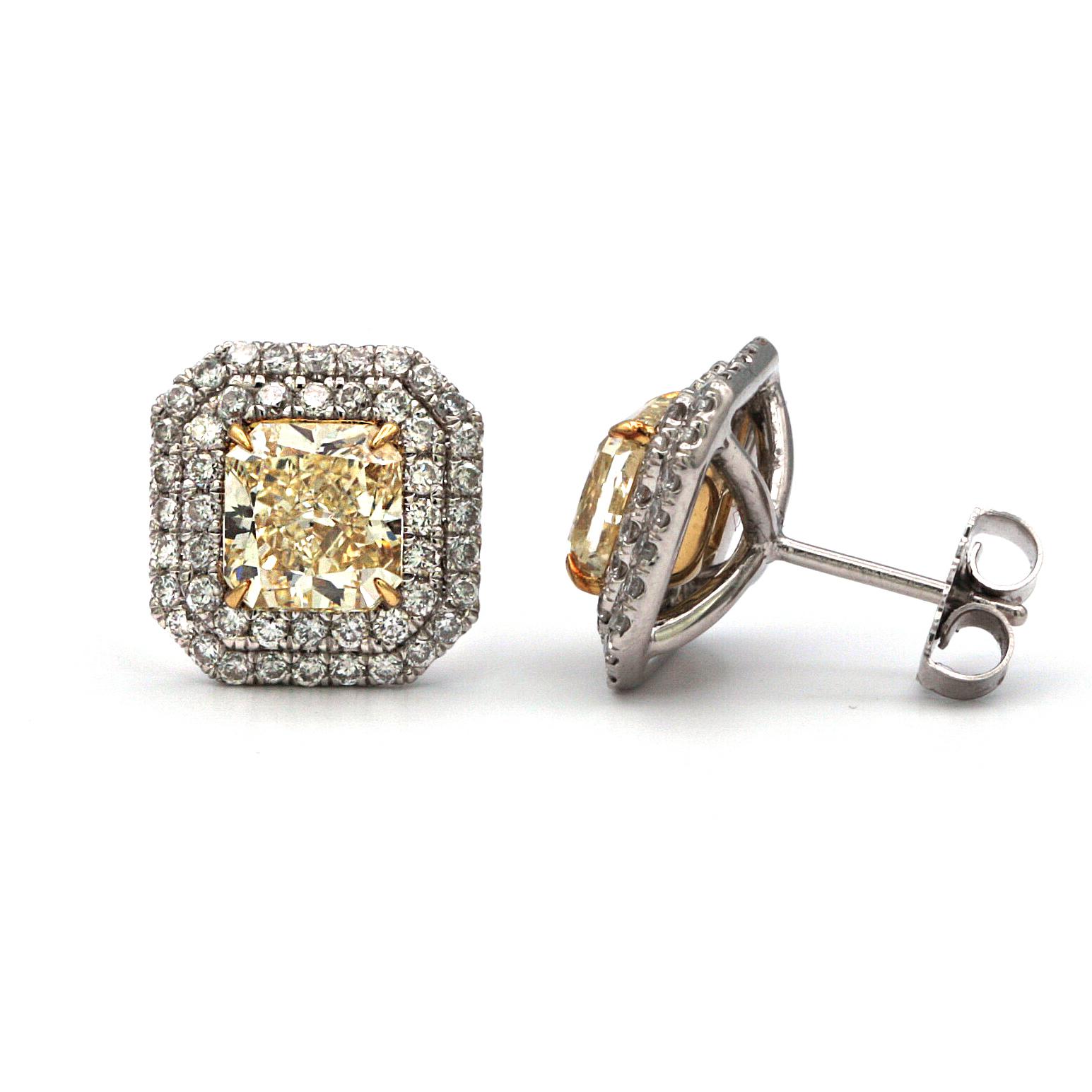 These stunning custom-made platinum diamond stud earrings feature two radiant shape Canary yellow diamonds weighing 4.10 carats.. The center diamonds have a double row halo of white diamonds of 1.12 carats.