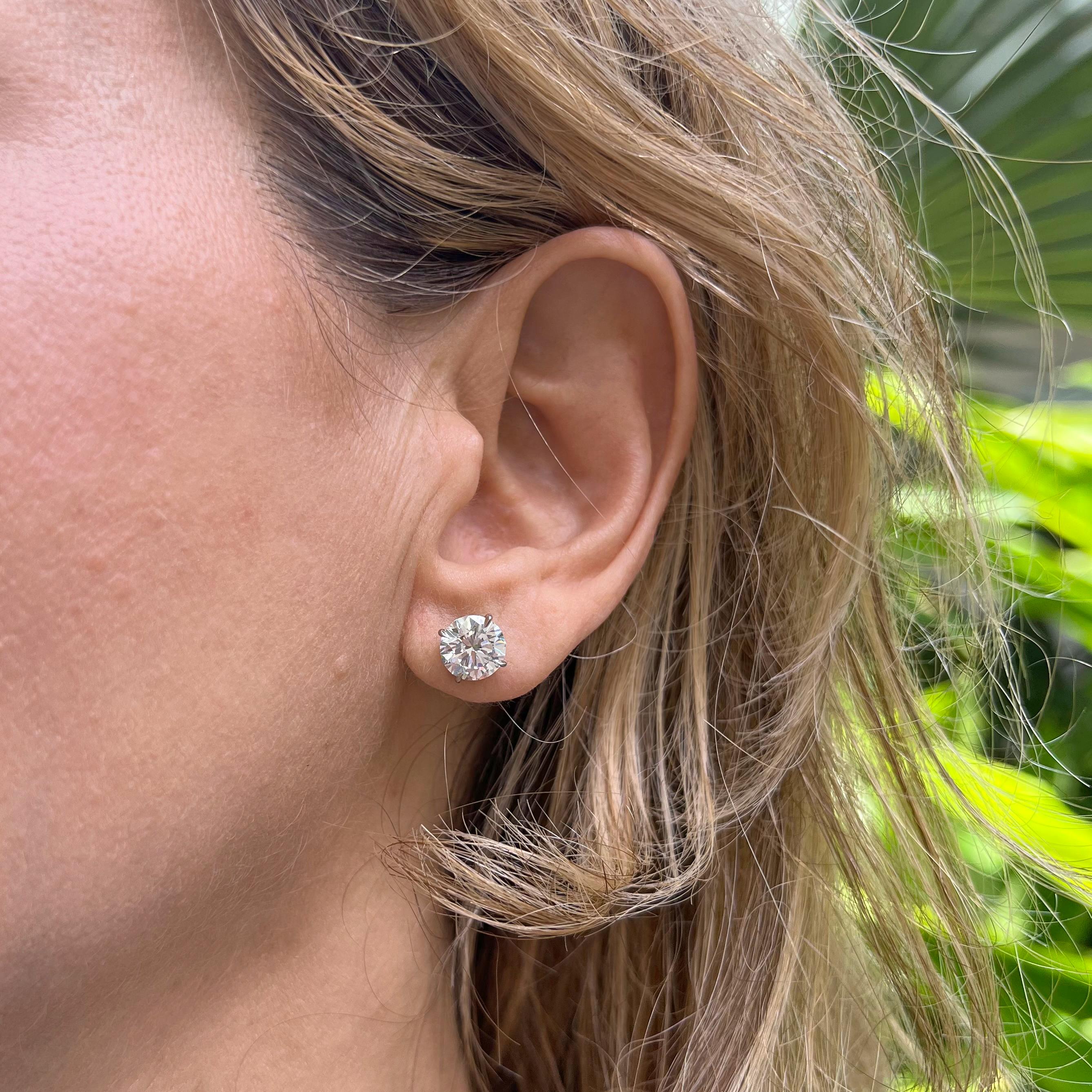 Round brilliant-cut diamond stud earrings, featuring a pair of meticulously-matched near-colorless diamonds weighing 4.02 total carats, the diamonds secured in four-prong platinum martini settings with posts for pierced ears. Both diamonds are